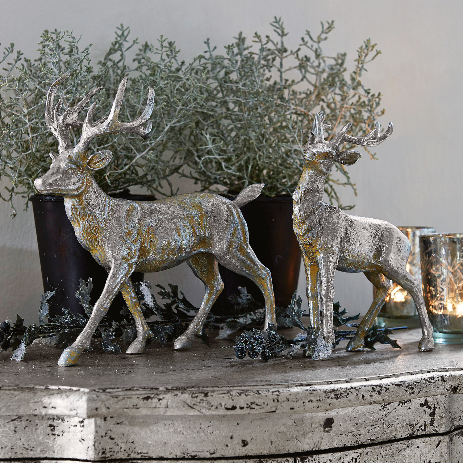 Hirsche 2er Set Rudy & Son Zwei silberne Hirschdekorationen aus Kunststoff auf rustikalem Sideboard mit Pflanzen und Kerzen