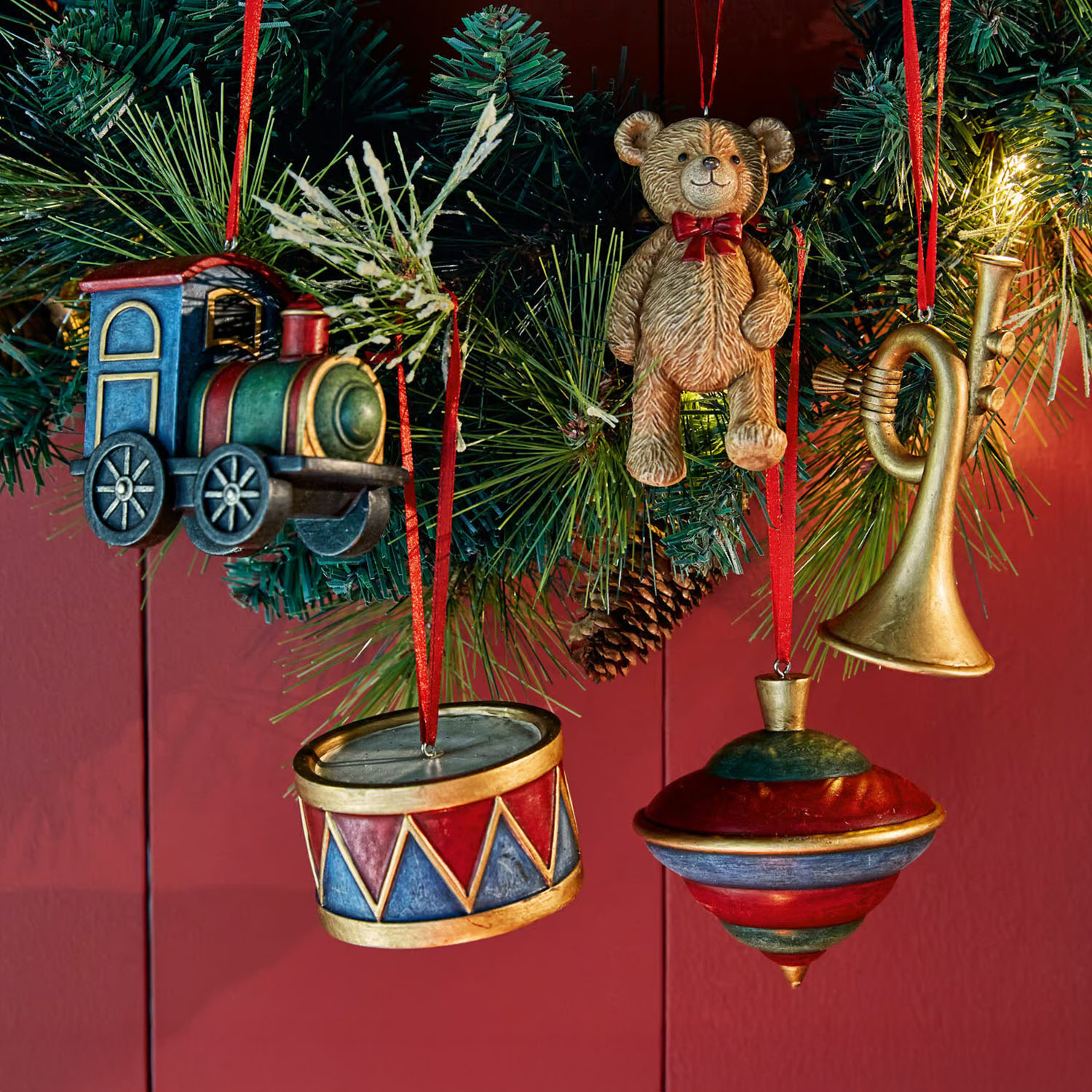 Bunte Holz-Weihnachtsanhänger: Lokomotive, Teddybär, Trommel, Kreisel und Trompete an grüner Tannenzweig