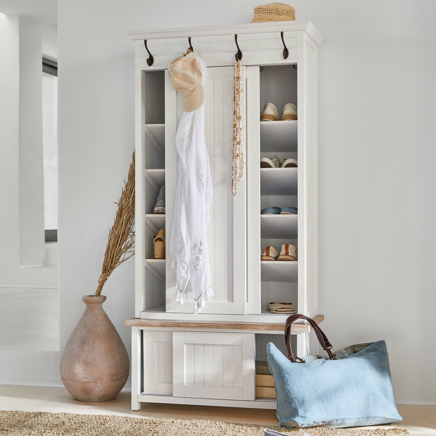 Garderobe Remerton Weisse Holzschuhschrank mit Haken und Regalen, blaue Tasche und Strohhut als Dekoration