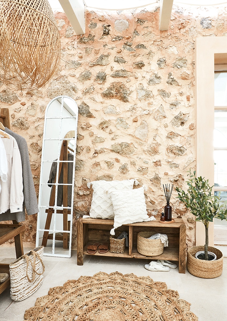 Gemütliche Ecke mit Holzbank, weissen Kissen und natürlichem Juteteppich im Boho-Stil