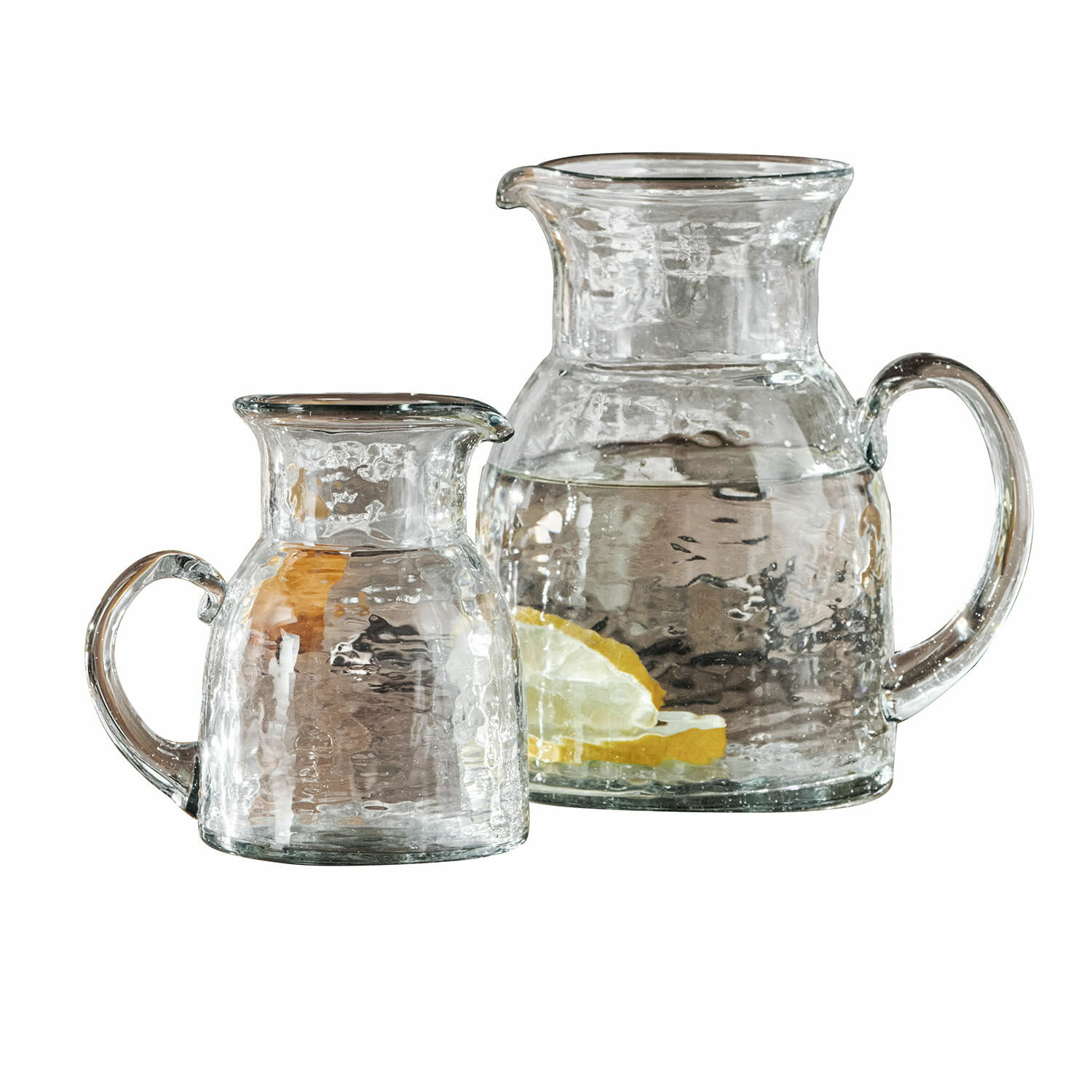 Krug 2er Set Zamirah Set aus zwei transparenten Glaskrügen mit Griffen, einer mit Zitronenscheiben und Wasser gefüllt.