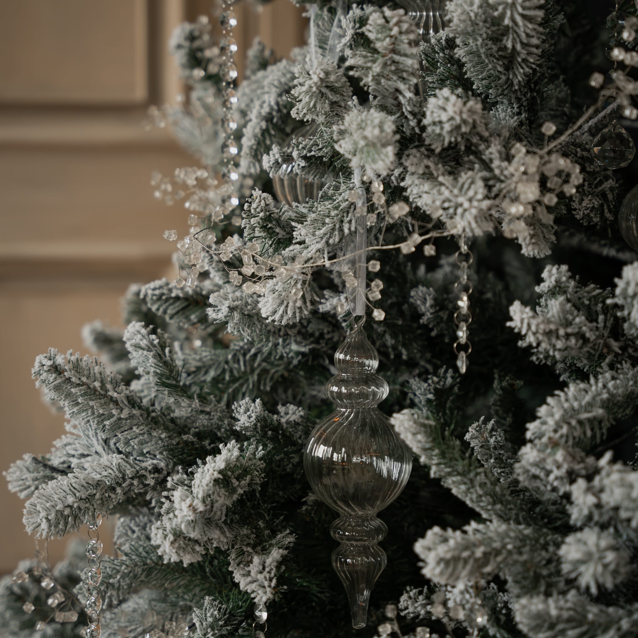 Künstlicher Weihnachtsbaum mit weissem Schnee und transparenten Glasornamenten