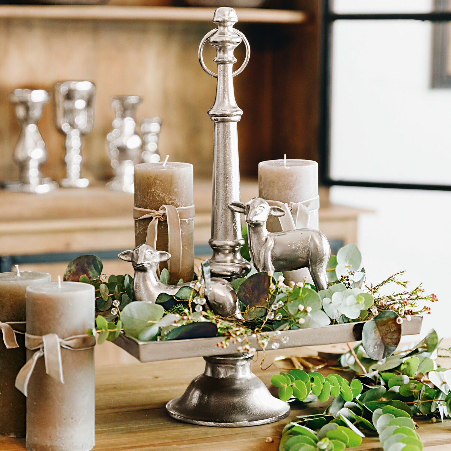 Stylebox Osterlamm Osterlamm Silberne Metall-Etagere mit Kerzen, grünen Blättern und dekorativen Schaf-Figuren als Tischdekoration