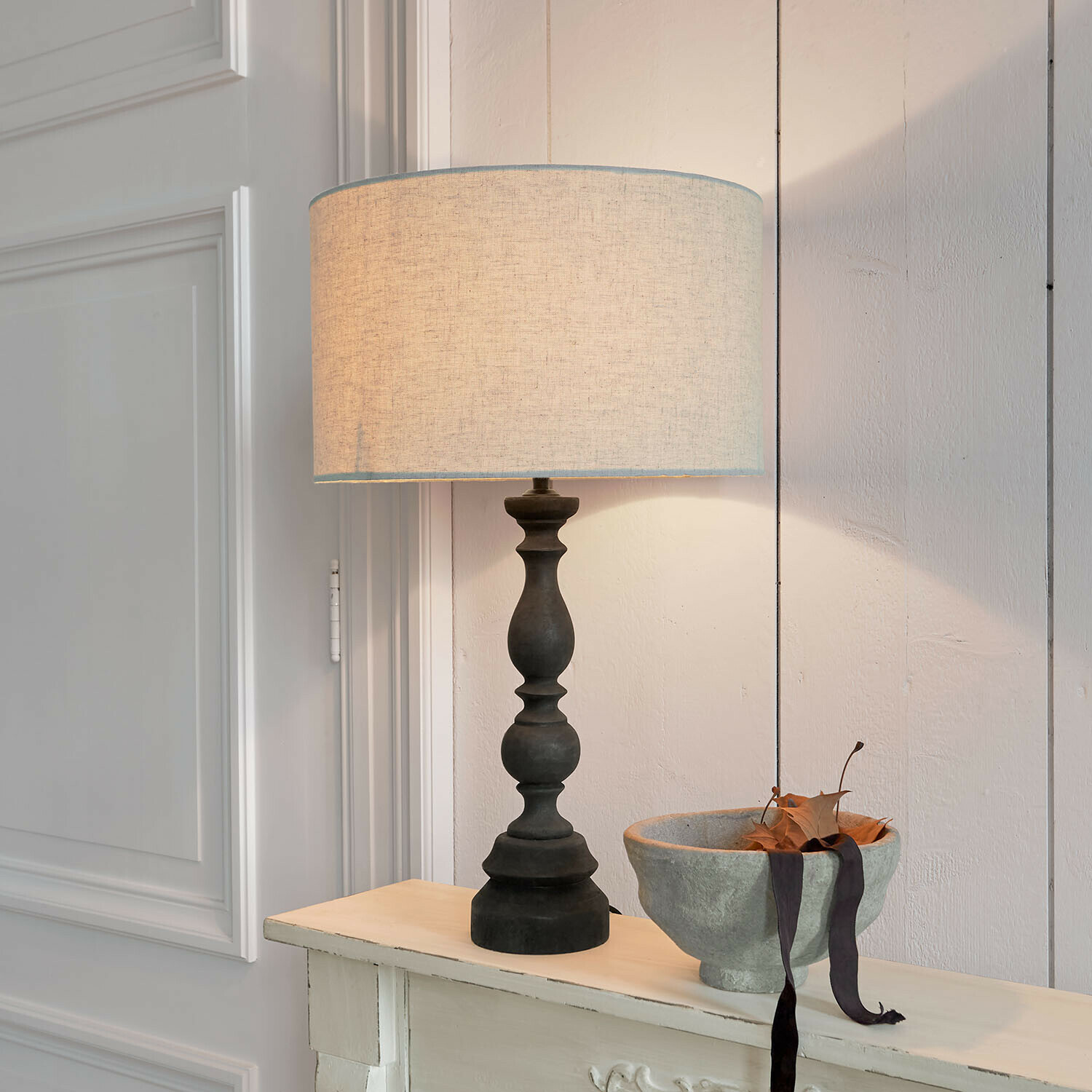 Tischlampe mit schwarzem Sockel und beigem Lampenschirm auf hellem Hintergrund, Wohnaccessoire