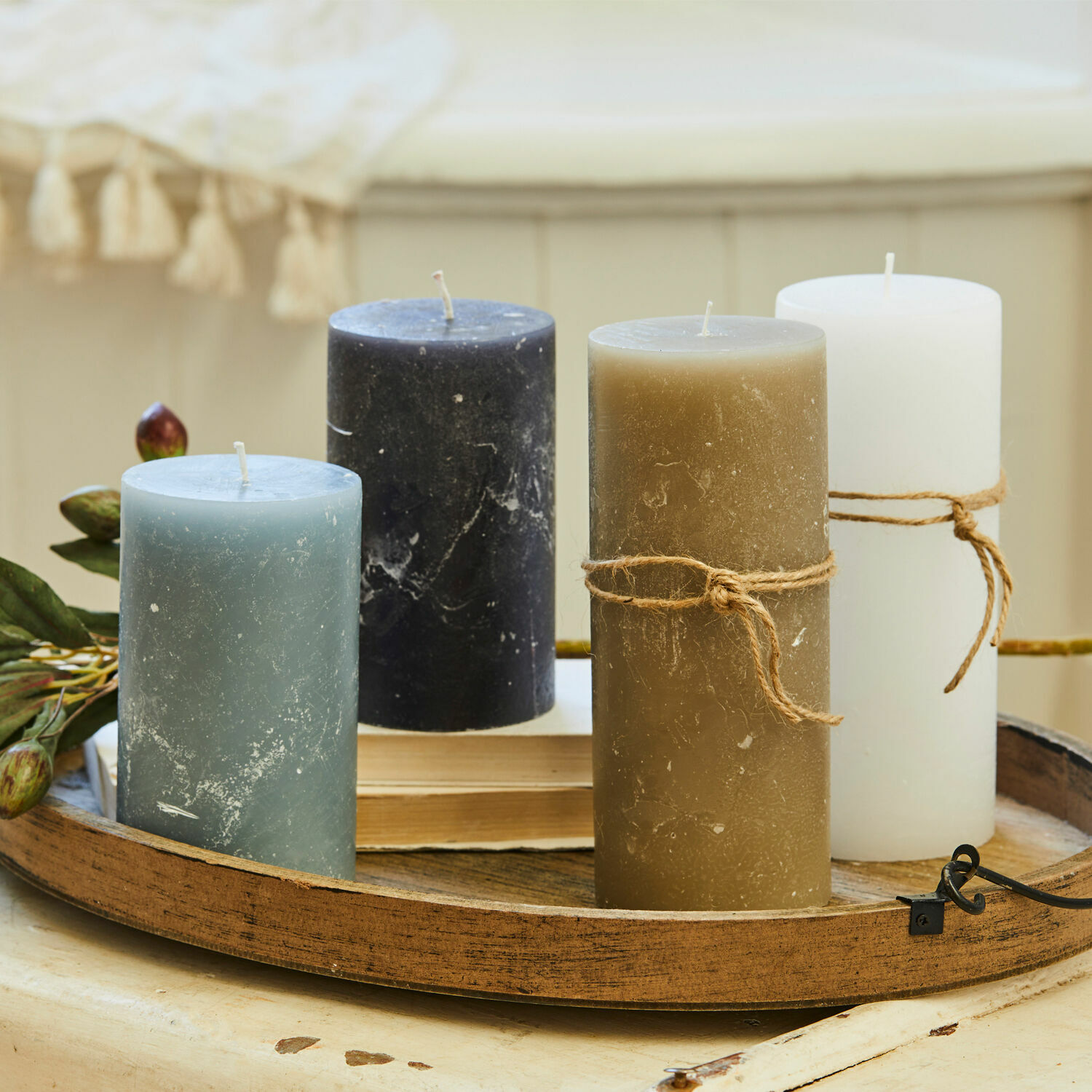 Set mit vier Kerzen in Blau, Schwarz, Braun und Weiss auf einem dekorativen Holztablett