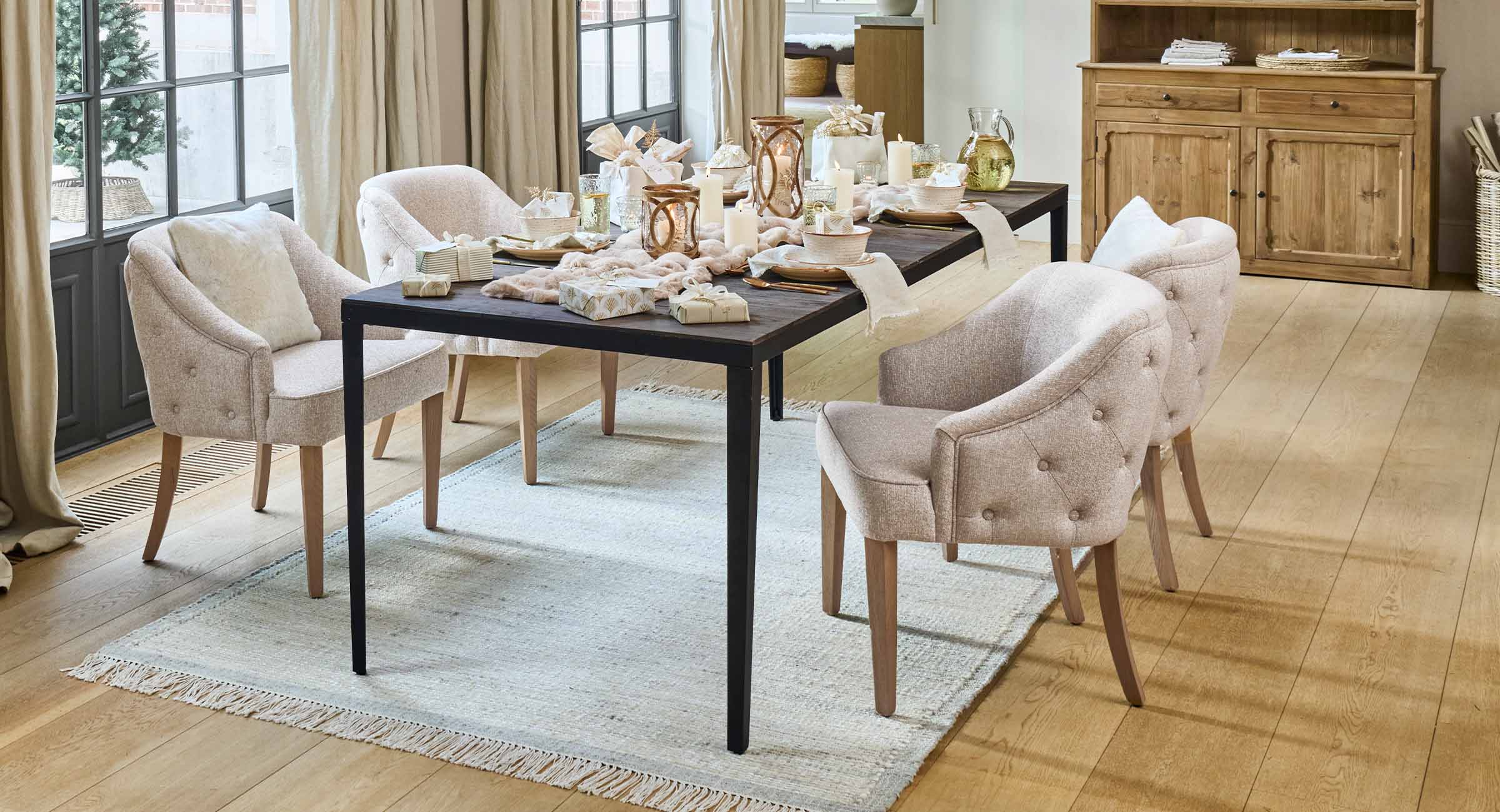 Helle beige Polsterstühle mit Holzbeinen an dunklem Esstisch mit Kerzen und Dekorationen im Esszimmer
