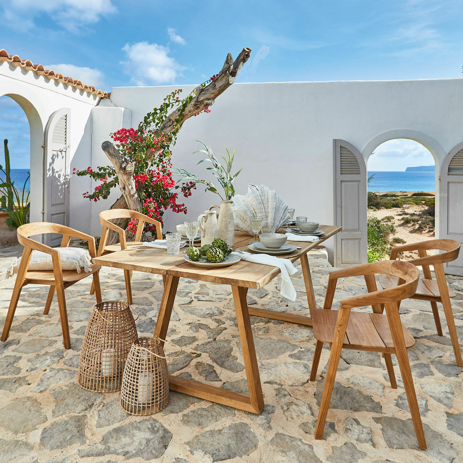 Tisch Saulny Gartenmöbel-Set aus Teakholz mit Stühlen und Tisch auf steinernem Sitzplatz mit Meerblick