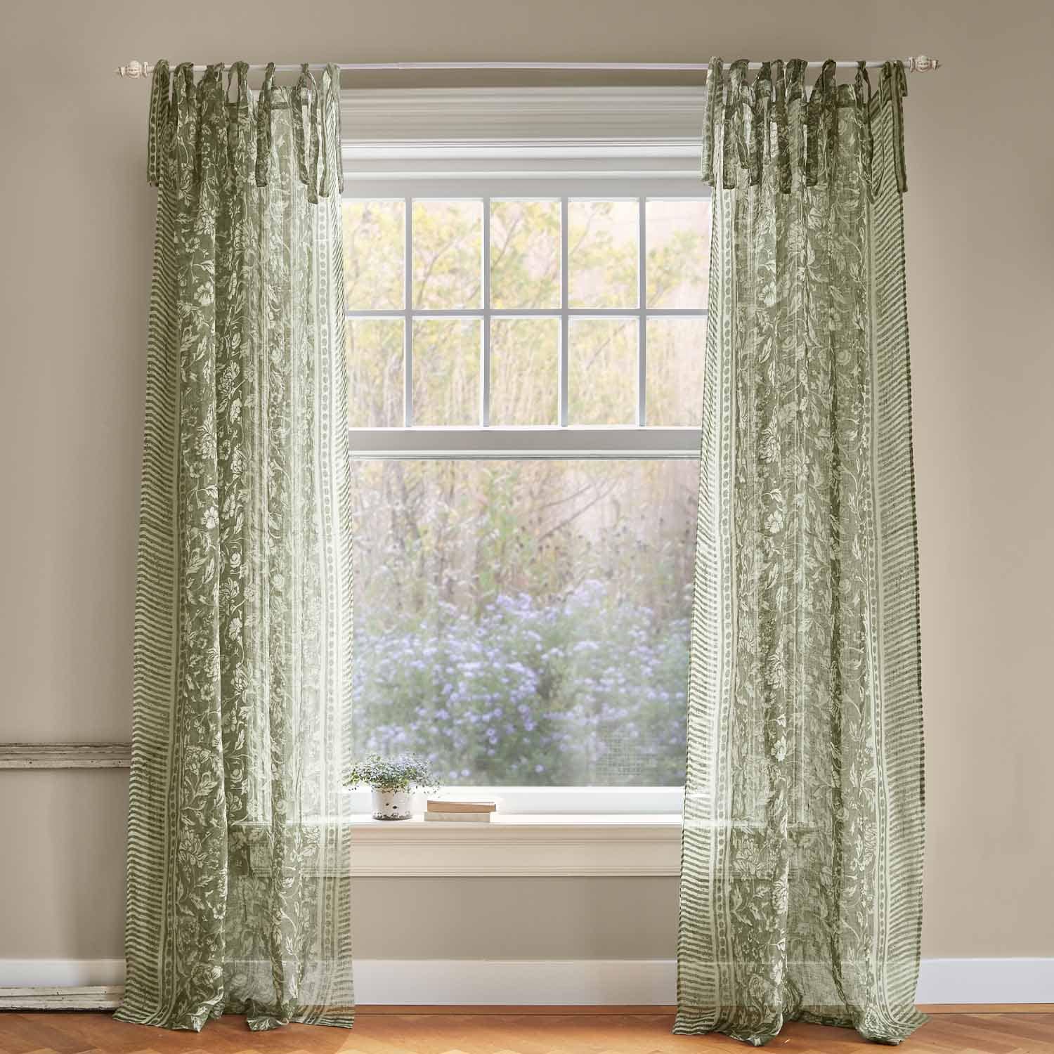Grüne, transparente Vorhänge mit Blumenmuster am Fenster, leichte Stoffdekoration für Innenräume.