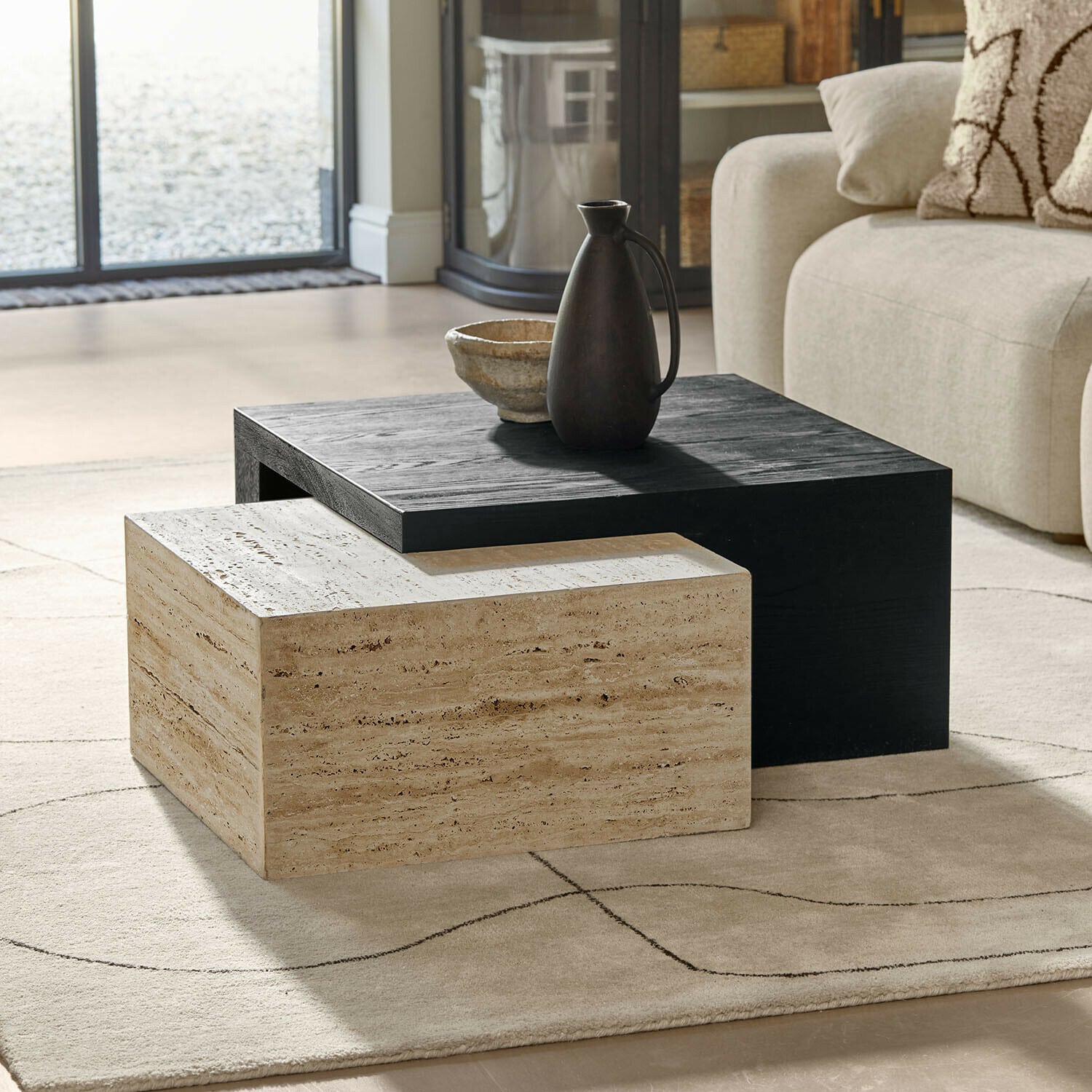 Moderne Couchtische aus schwarzem Holz und beigem Stein auf hellem Teppich im Wohnzimmer