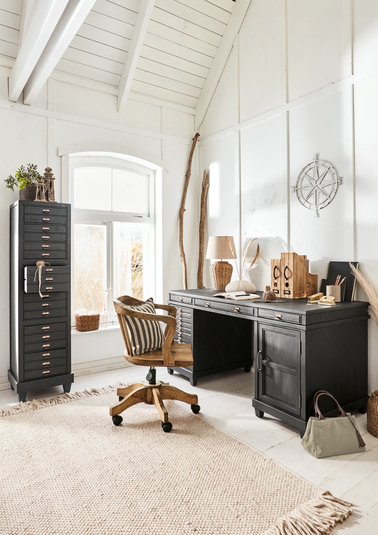 Schwarzer Holzschreibtisch und hoher Schubladenschrank in hellem, gemütlichem Arbeitszimmer