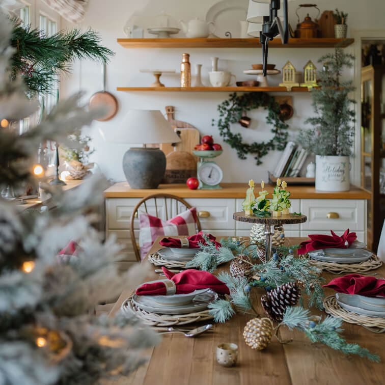 Weihnachtlich gedeckter Holztisch mit roten Servietten und natürlichen Tannenzapfen- und Zweigdekorationen