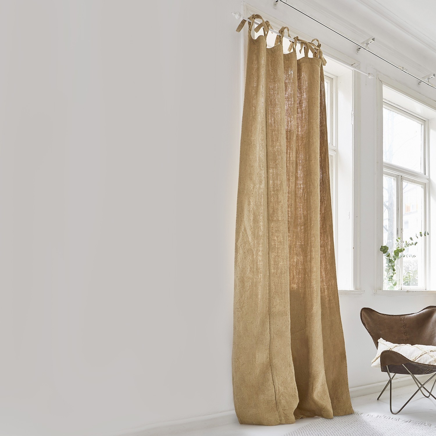 Gardine Uma Beiger Vorhang aus natürlichem Leinen in hellem Raum mit grossem Fenster und braunem Sessel