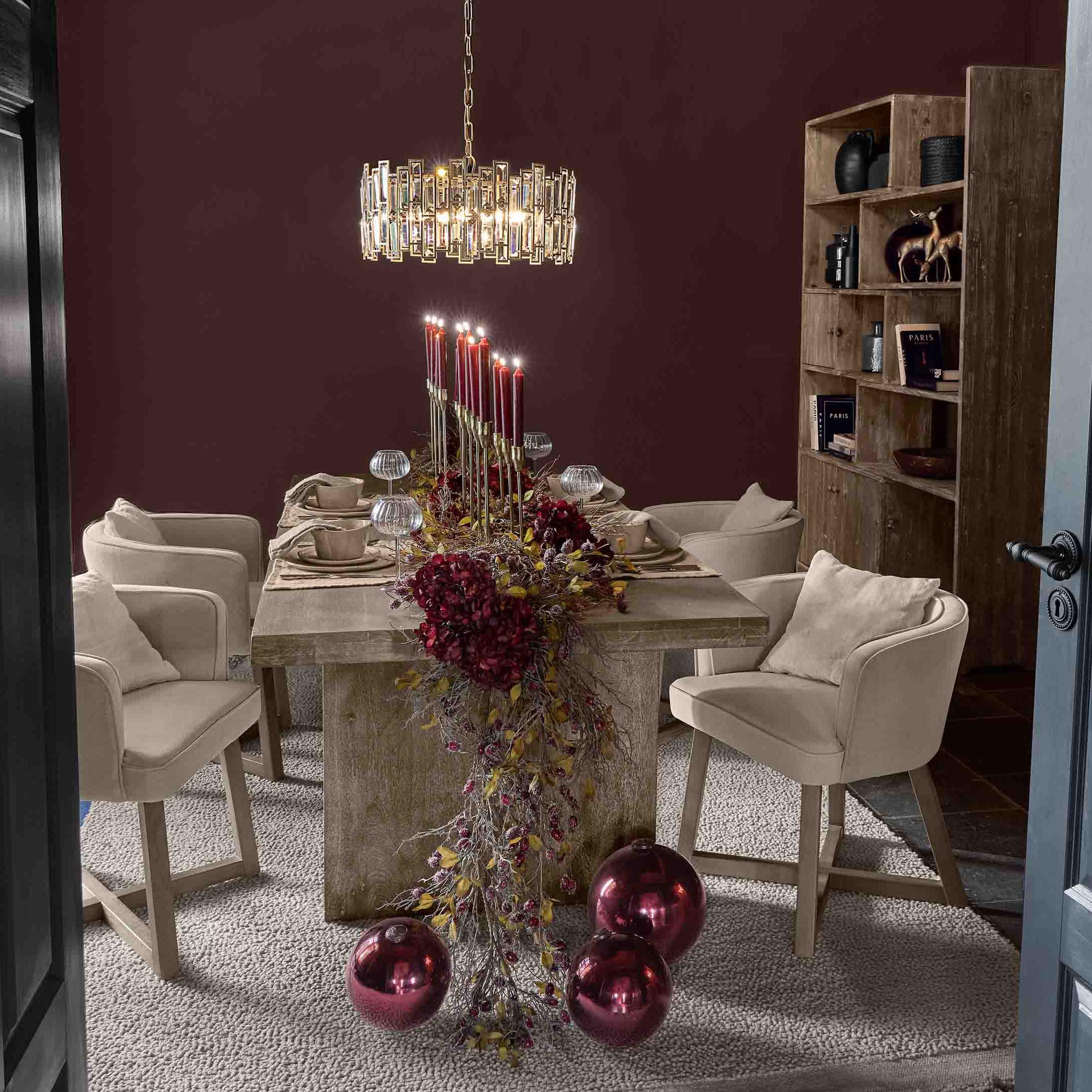 Esszimmer mit Holztisch, beigen Stühlen und roter Kerzen- und Weihnachtskugel-Dekoration