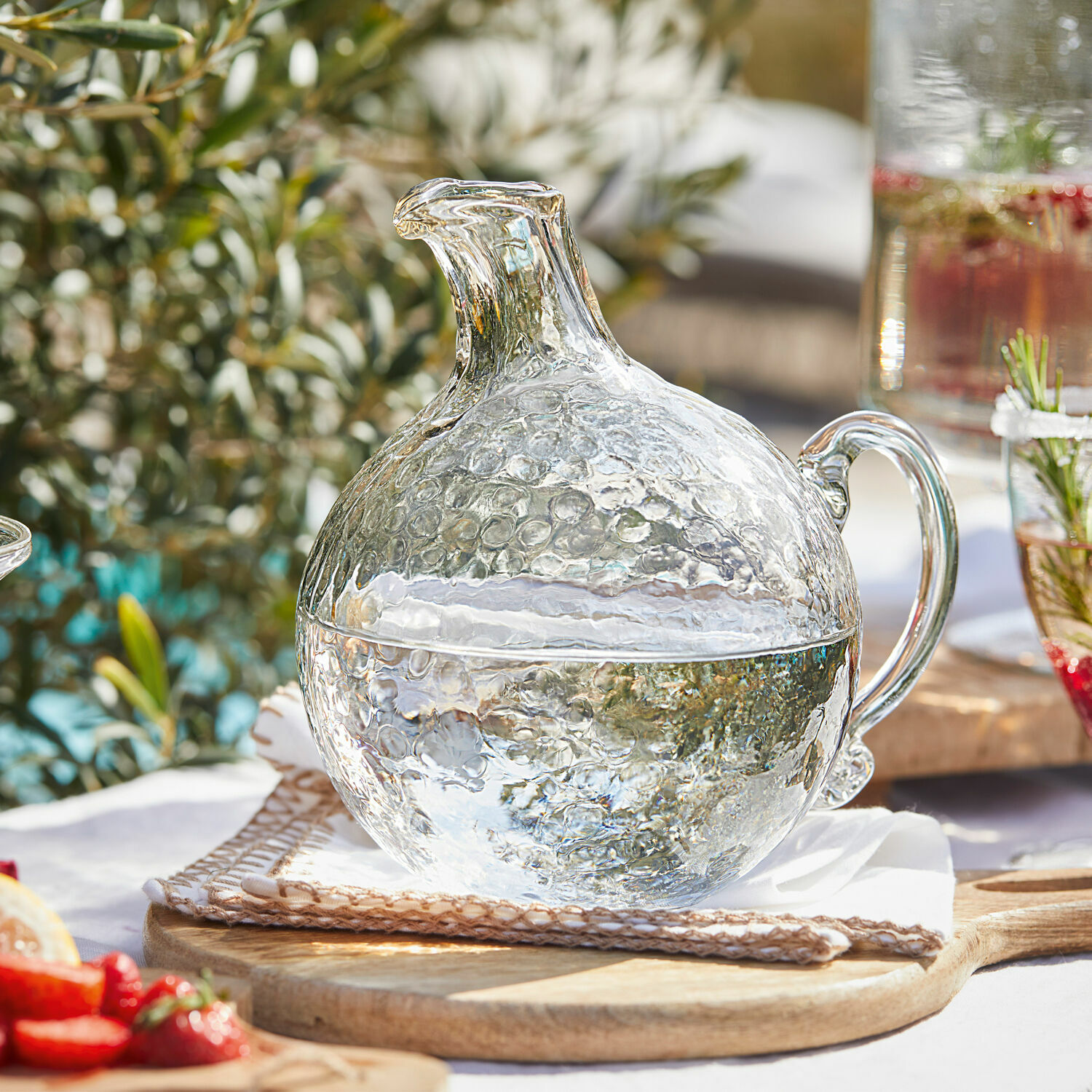Krug Valters Glaskrug mit Blasenstruktur, transparent, auf Holzbrett, ideal für Getränke und Sommerfeste.