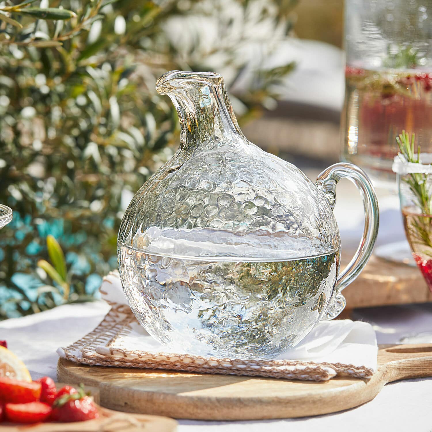 Krug Valters Glaskrug mit Blasenstruktur, transparent, auf Holzbrett, ideal für Getränke und Sommerfeste.