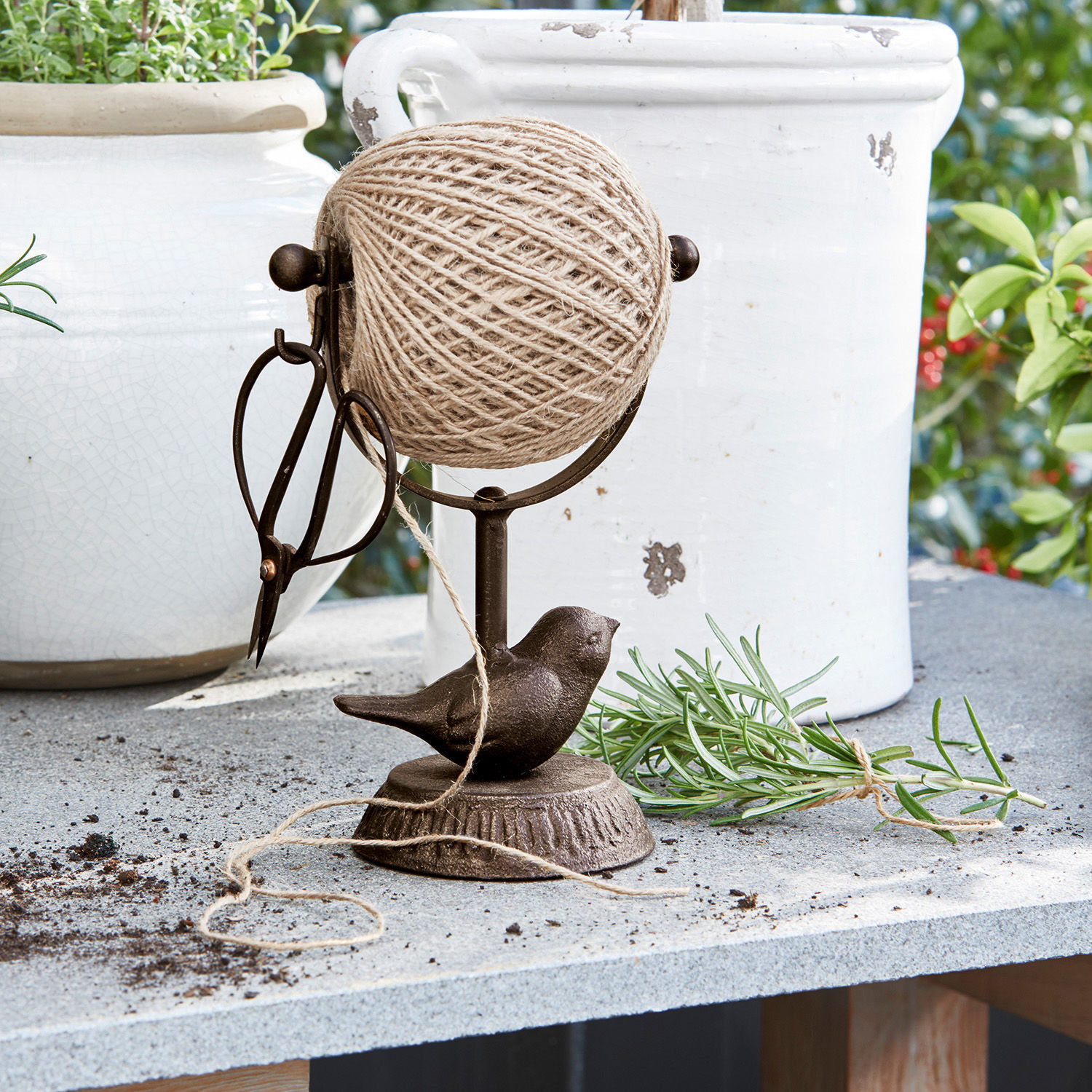Schnurhalter Ortolan Brauner Metallhalter mit Garnrolle, Schere und Vogel-Dekor auf Gartentisch aus Stein