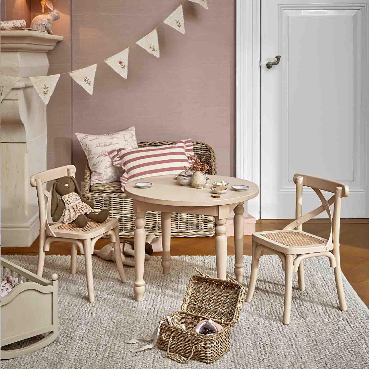 Runder Holztisch und zwei Stühle mit geflochtenem Sitz in hellem Beige im Kinderzimmer