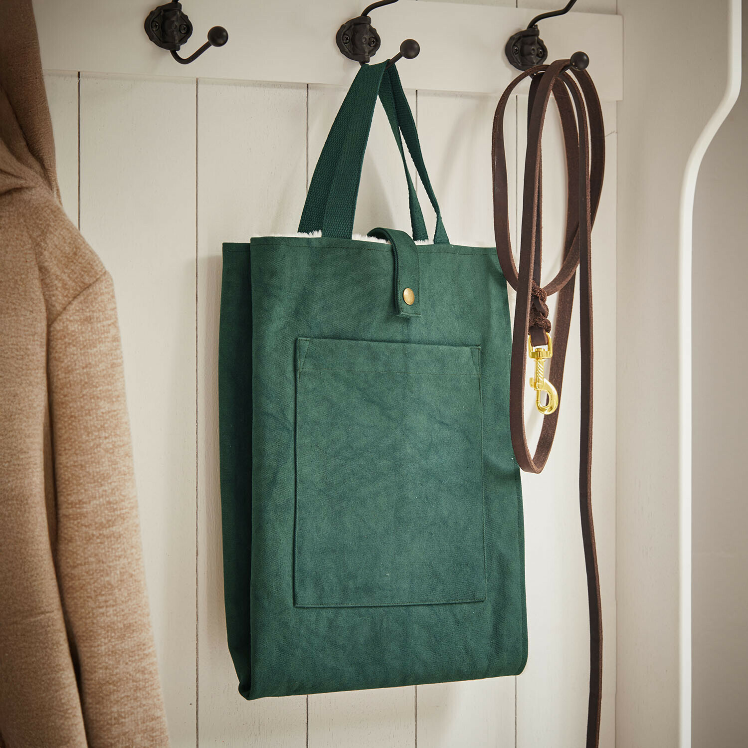 Haustiermatte Felliro Grüne Stofftasche an weissem Holzkleiderhaken neben brauner Leine und beigem Mantel