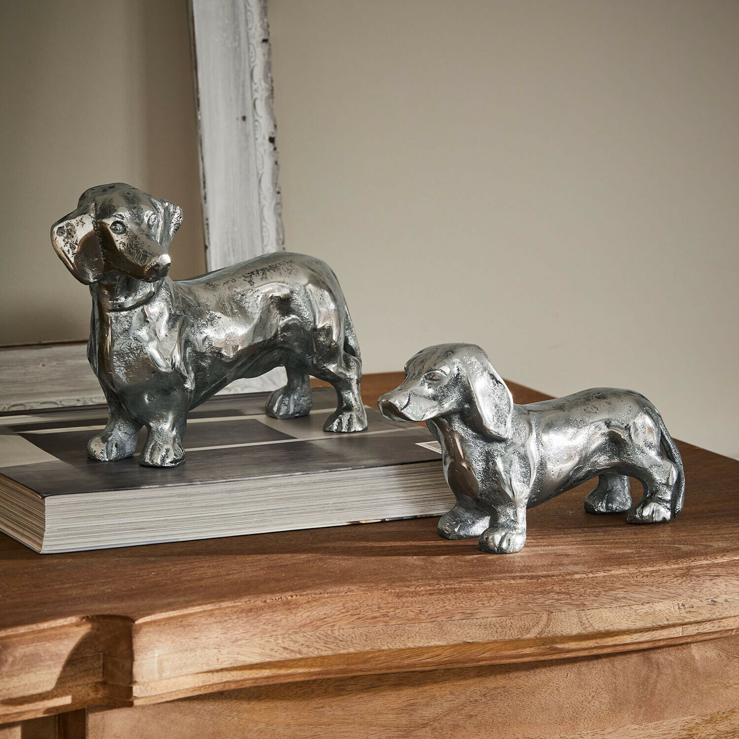 Deko-Hund 2er Set Calwen Zwei silberne Dackel-Figuren aus Metall auf Holztisch als elegante Wohnaccessoires