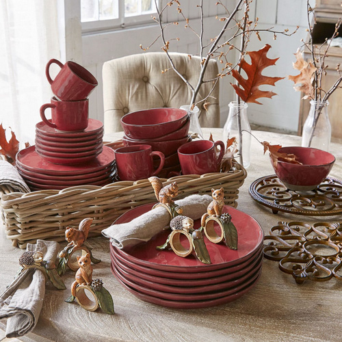 Rotes Keramikgeschirr-Set mit Tassen und Tellern im Weidenkorb, herbstliche Dekoration