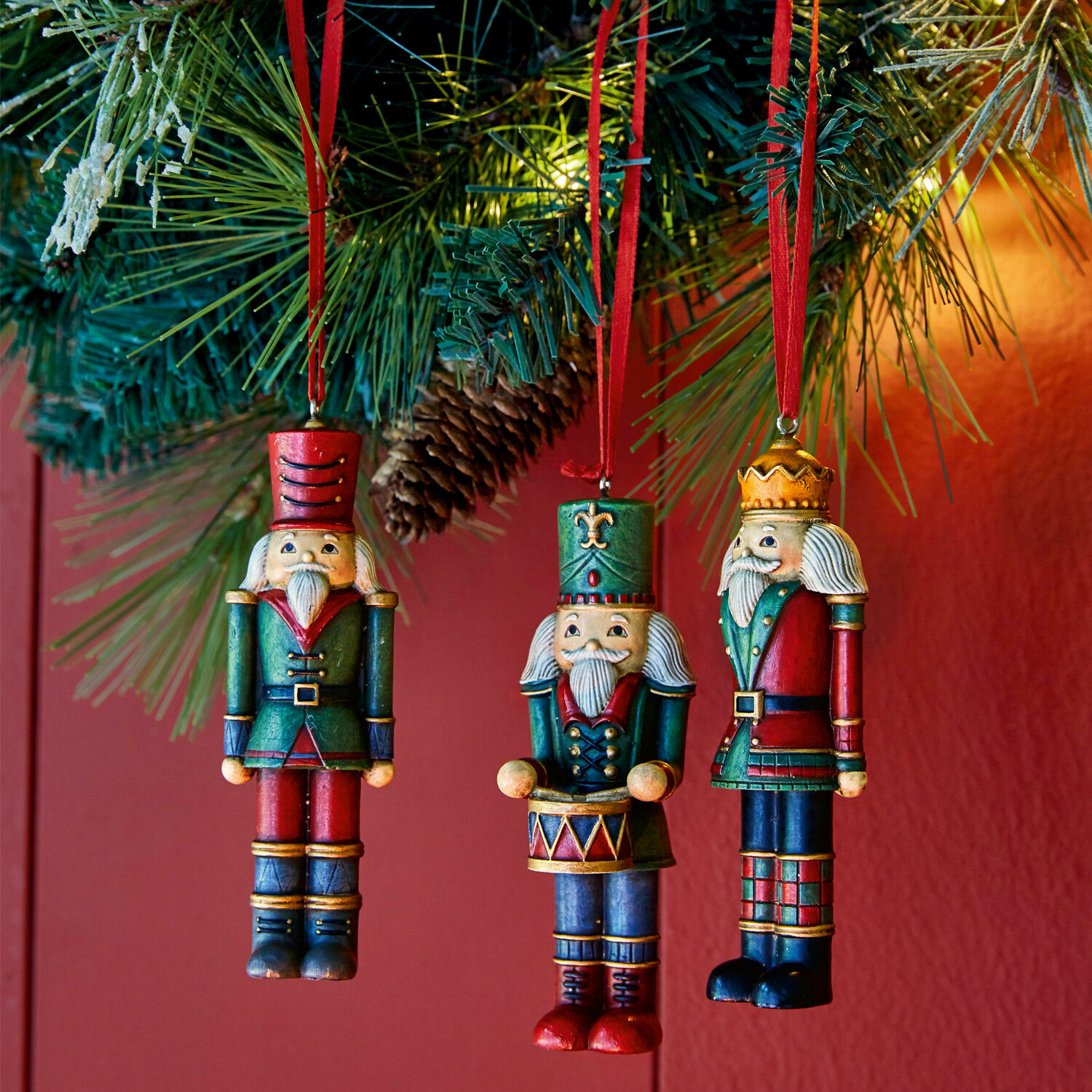 Anhänger 3er Set Laudat Drei hölzerne Weihnachtsanhänger in Form von roten und grünen Soldaten an einem Tannenzweig.