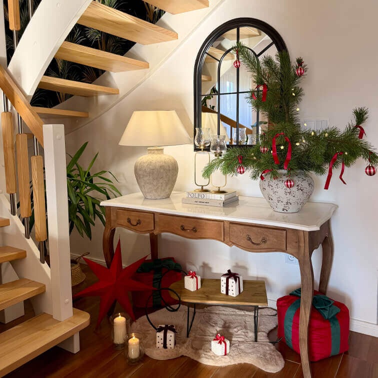 Holztisch mit Marmorplatte, Lampe und Weihnachtsdekoration aus grünen Zweigen mit roten Kugeln