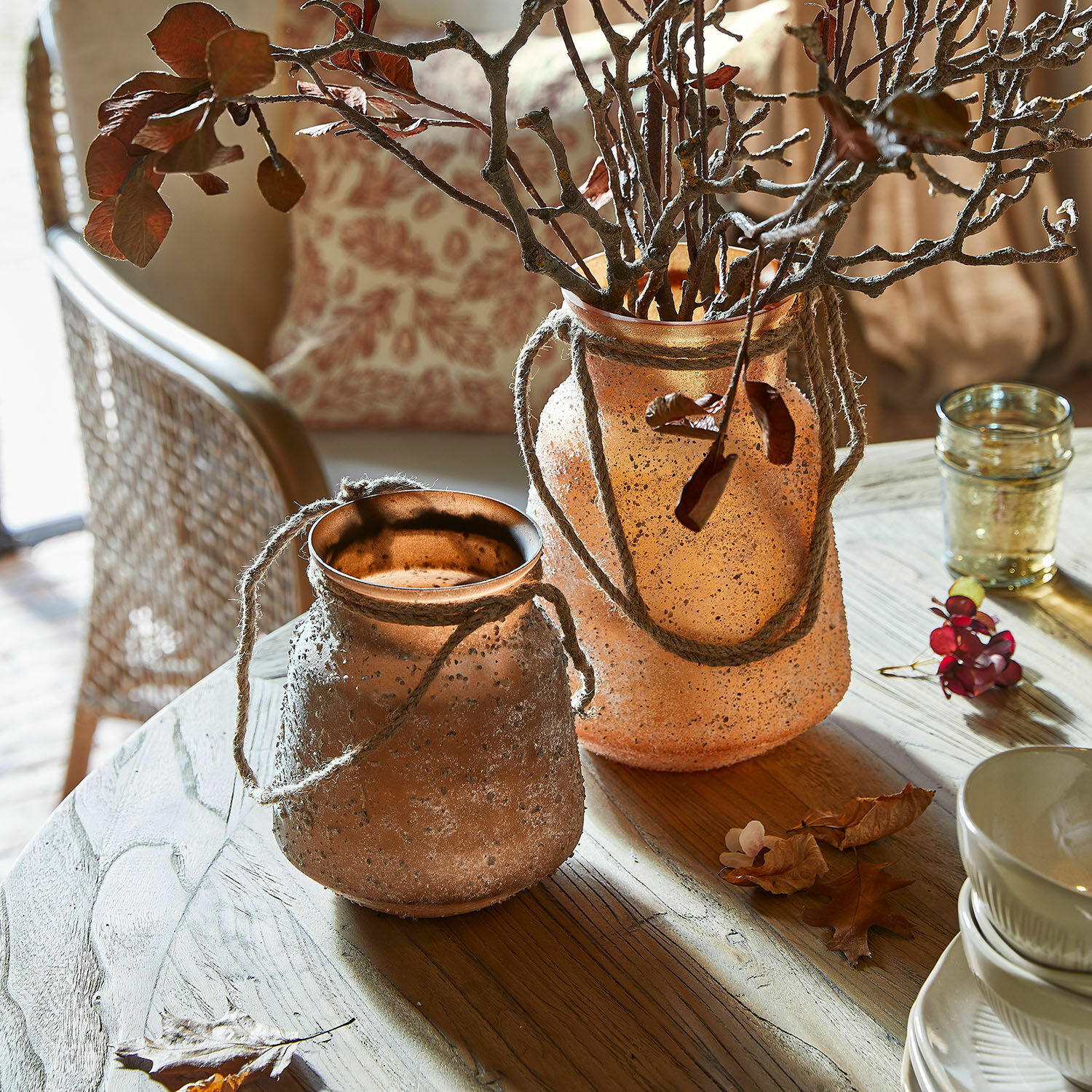 Vase 2er Set Querello Zwei dekorative Vasen aus mattiertem orangefarbenem Glas mit Kordeln auf einem Holztisch im Wohnzimmer.