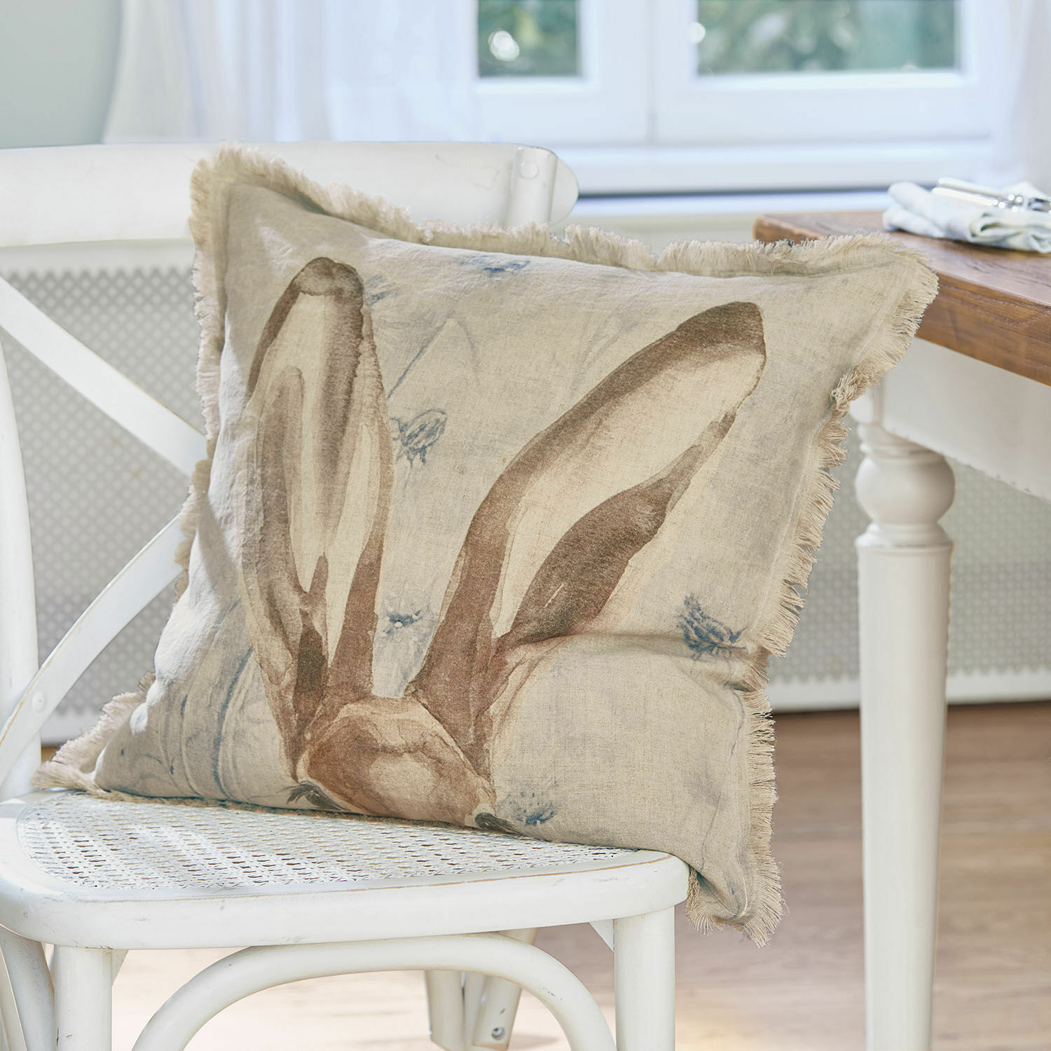 Kissenhülle Kameron Beiges Leinenkissen mit Hasenohren-Motiv auf weissem Stuhl als Wohnaccessoire