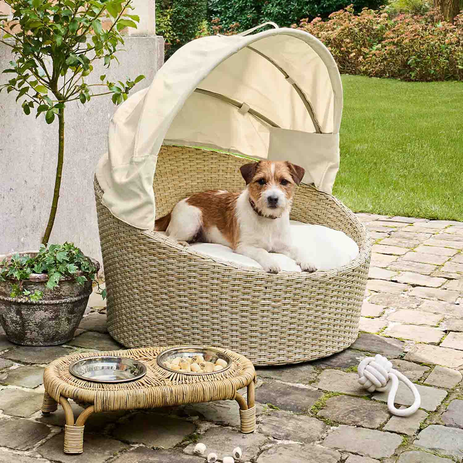 Rundes Hundebett aus beigem Rattan mit cremefarbenem Dach und Kissen für den Aussenbereich