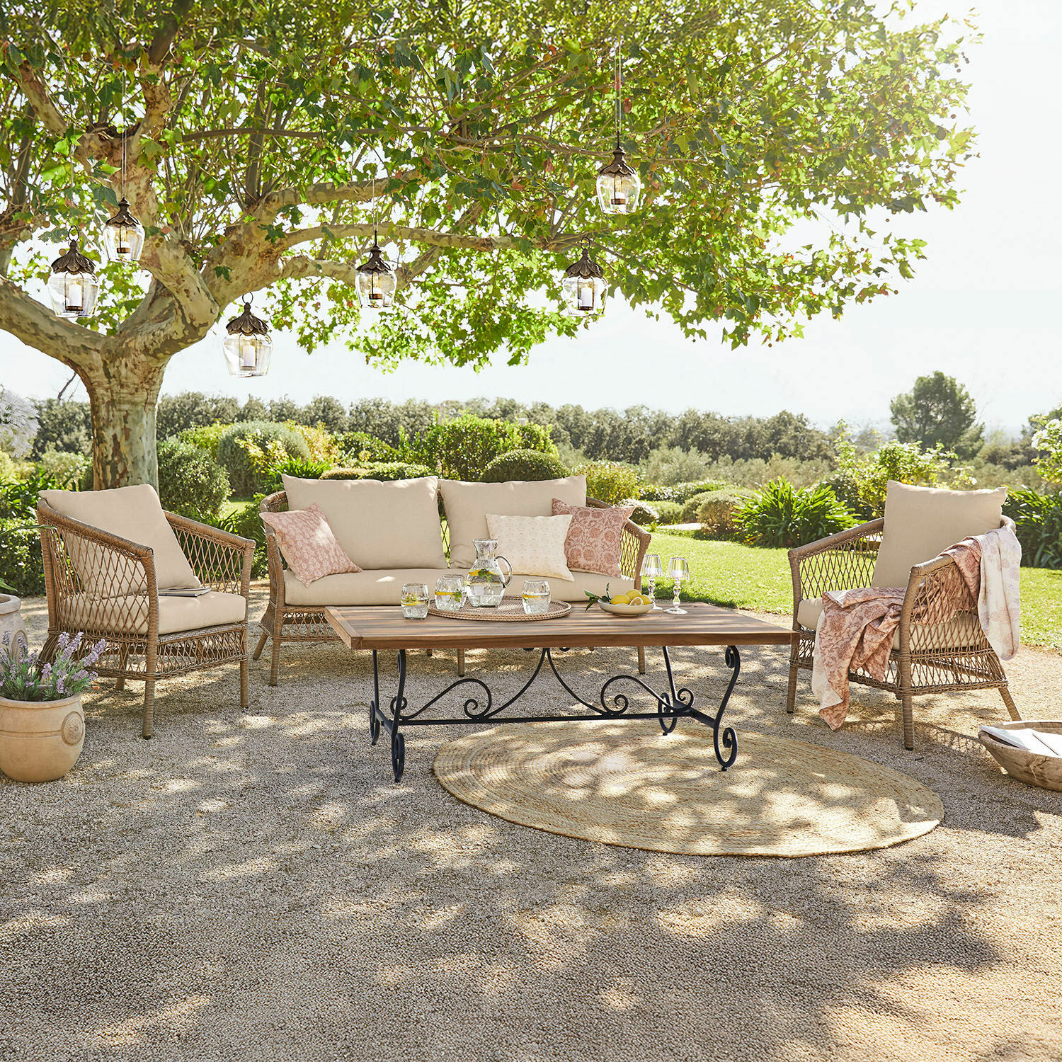 Sitzgruppe Farington Gartenmöbel-Set aus Rattan mit beigen Polstern und Holztisch auf der Terrasse im grünen Garten