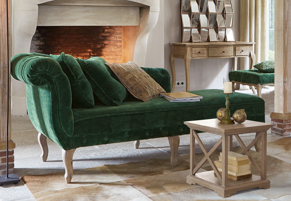 Klassisches grünes Samtsofa mit Holzbeinen in elegantem Wohnzimmer mit Cheminée