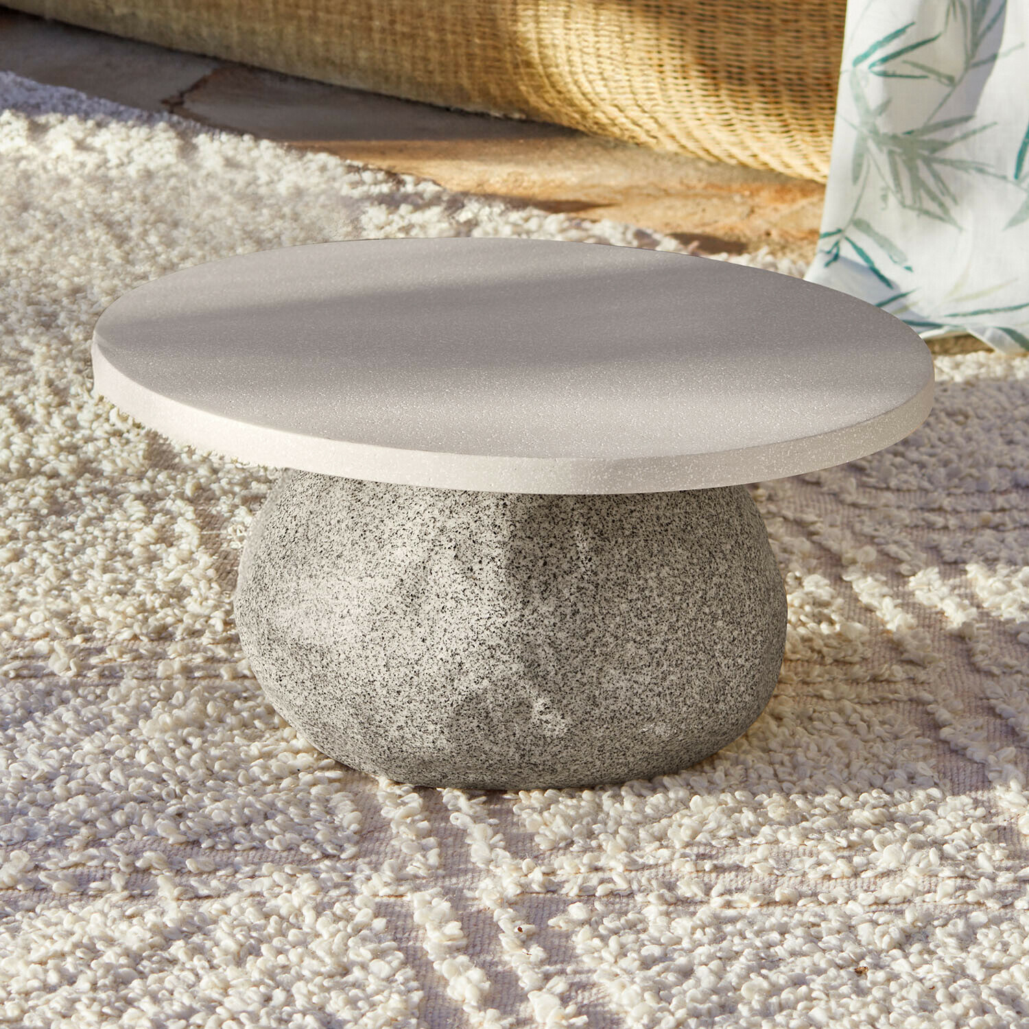 Runder Couchtisch aus grauem Stein auf hellem Teppich, modernes Wohnzimmerdesign