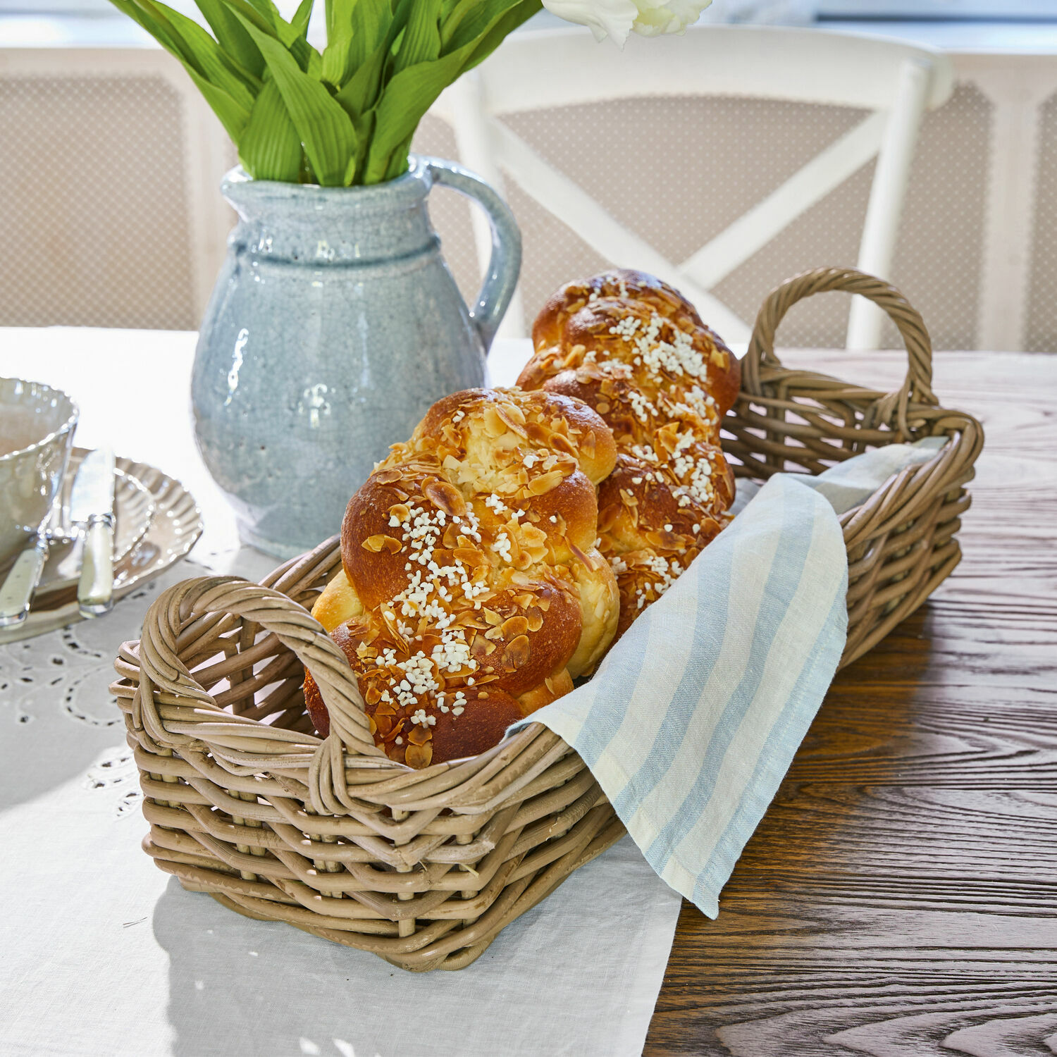 Korb Balmis Weidenkorb mit zwei Griffen, gefüllt mit Hefezopf und Leinenstoff auf Holztisch