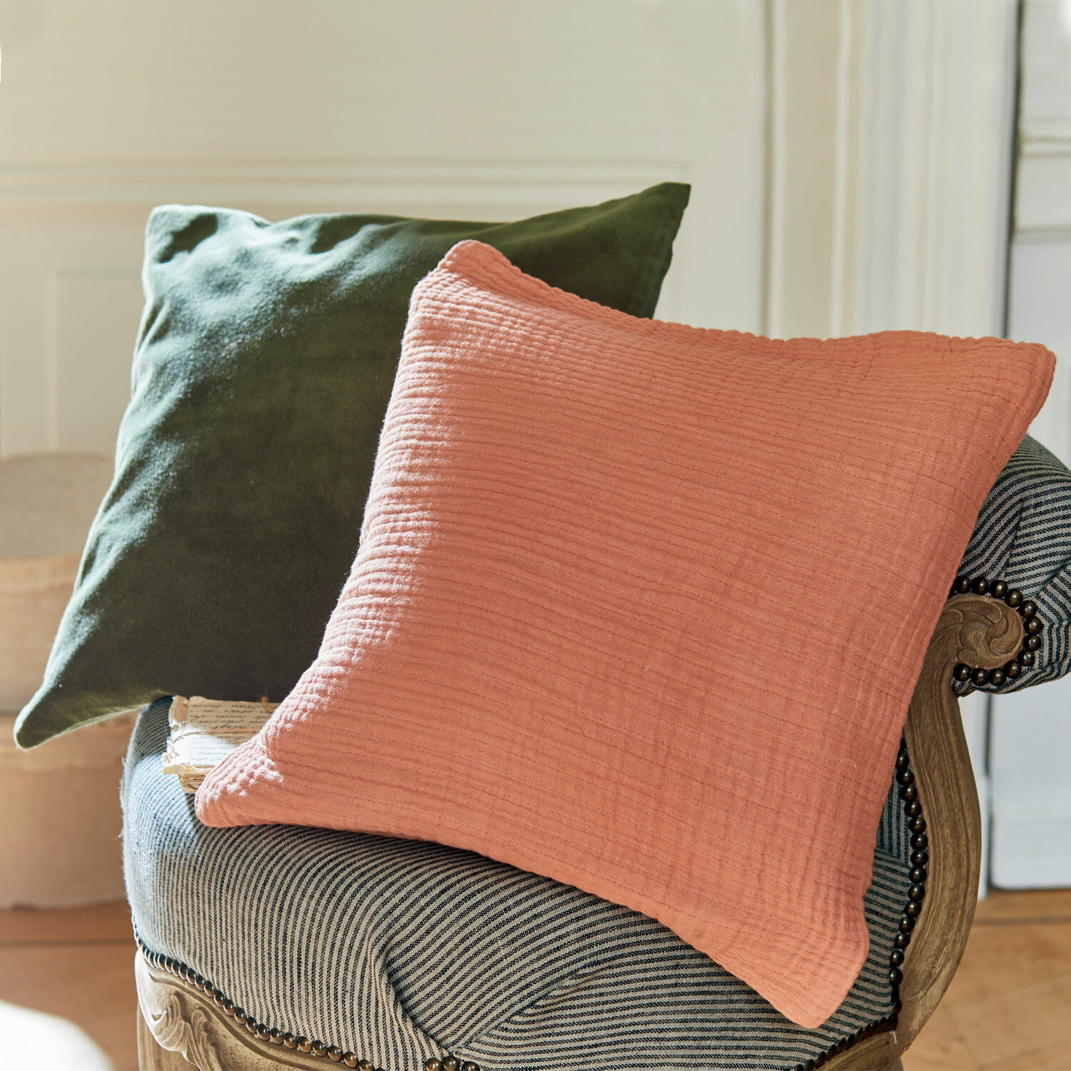 Zweifarbiges Baumwollkissen in Rosa und Grün auf gestreiftem Sessel
