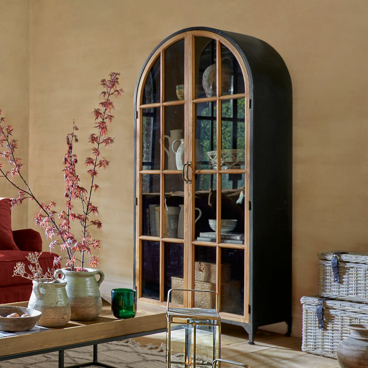 Schrank Mardilly Schrank mit abgerundetem schwarzem Metallkorpus und Holztüren mit Glas im Wohnzimmer.