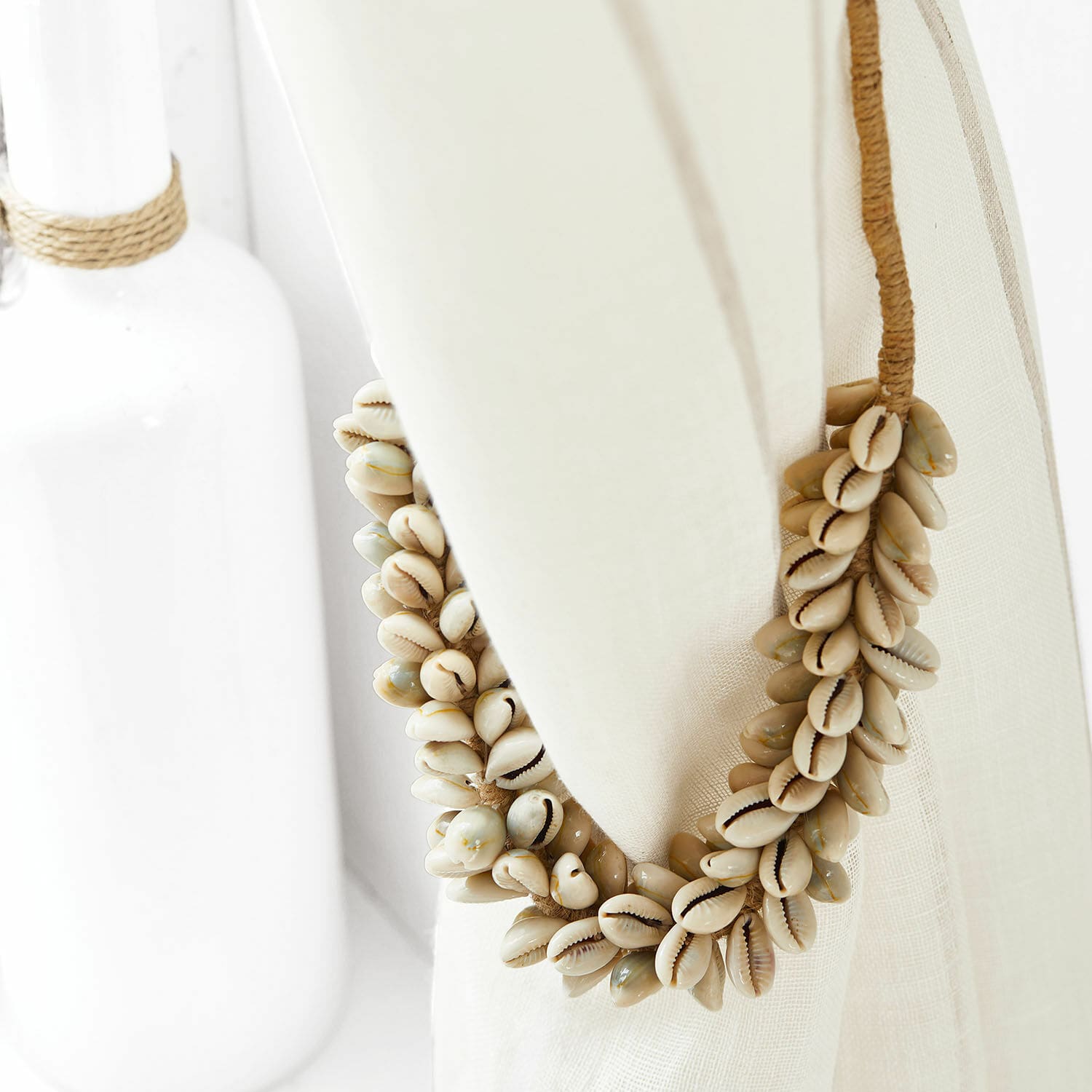 Gardinenhalter Alix Dekorativer Kranz aus natürlichen Muscheln in Beige auf Leinenstoff