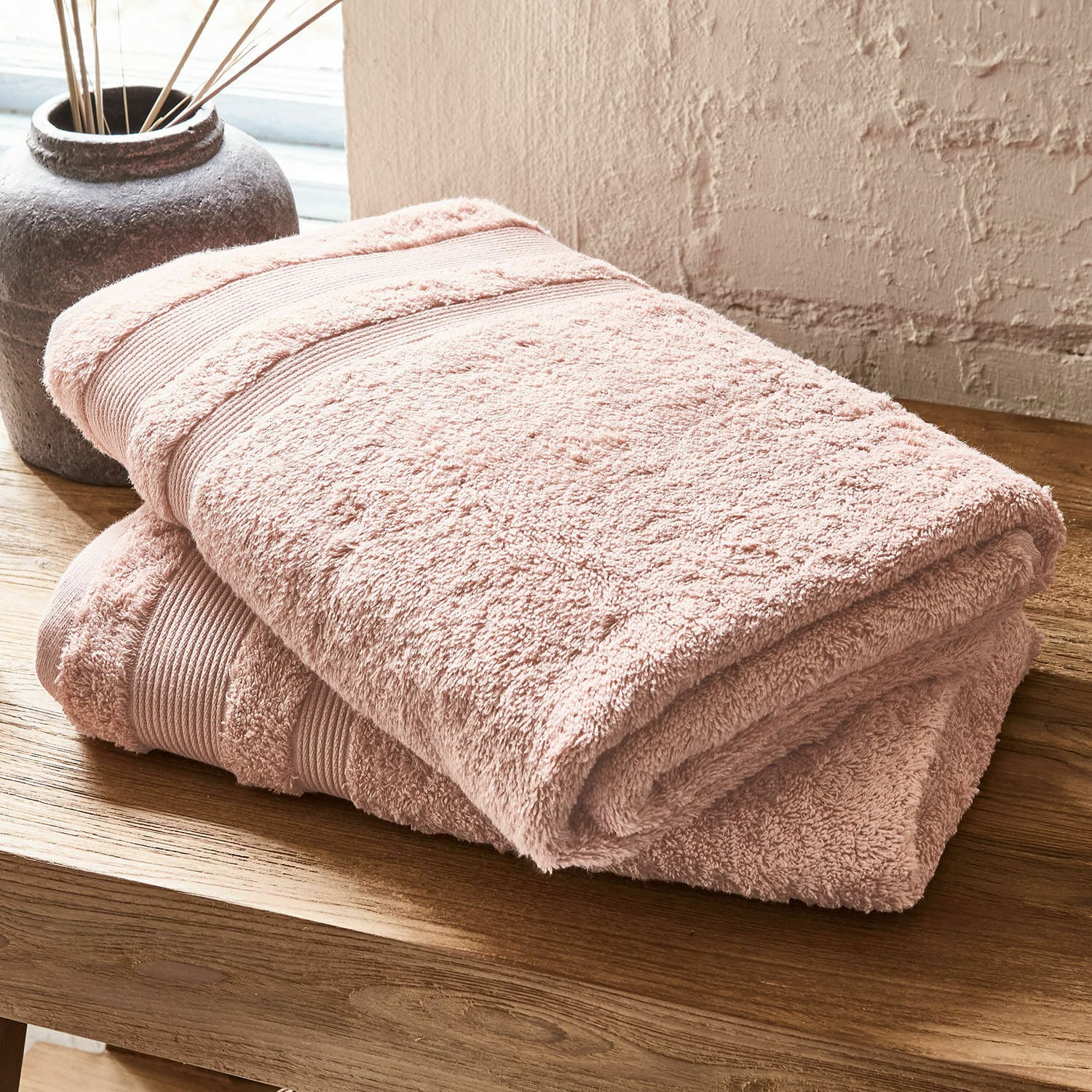 Badetuch 2er Set Bourogne Weiches rosa Baumwollhandtuch auf Holztisch, ideal für das Badezimmer und den täglichen Gebrauch.