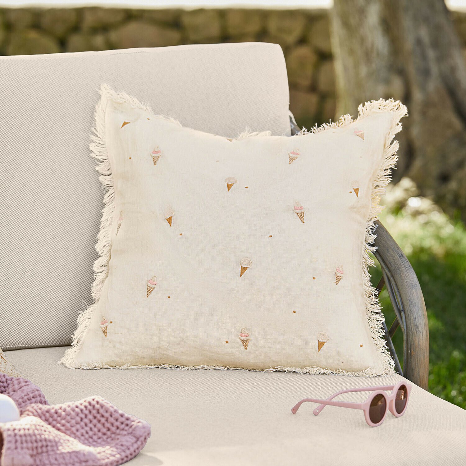 Kissenhülle Toffelis Beiges Leinenkissen mit Fransen und Eistüten-Motiv auf hellem Sofa im Garten