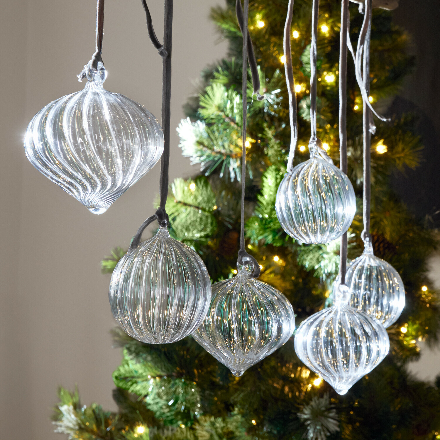 Weihnachtskugel 6er Set Bavella Transparente Glas-Weihnachtskugeln mit Rillen vor einem beleuchteten Tannenbaum