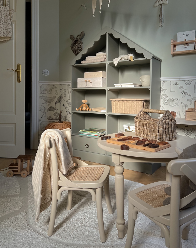 Kinderzimmer mit grauem Holzregal in Hausform und beigen Stühlen mit geflochtenem Sitzgeflecht