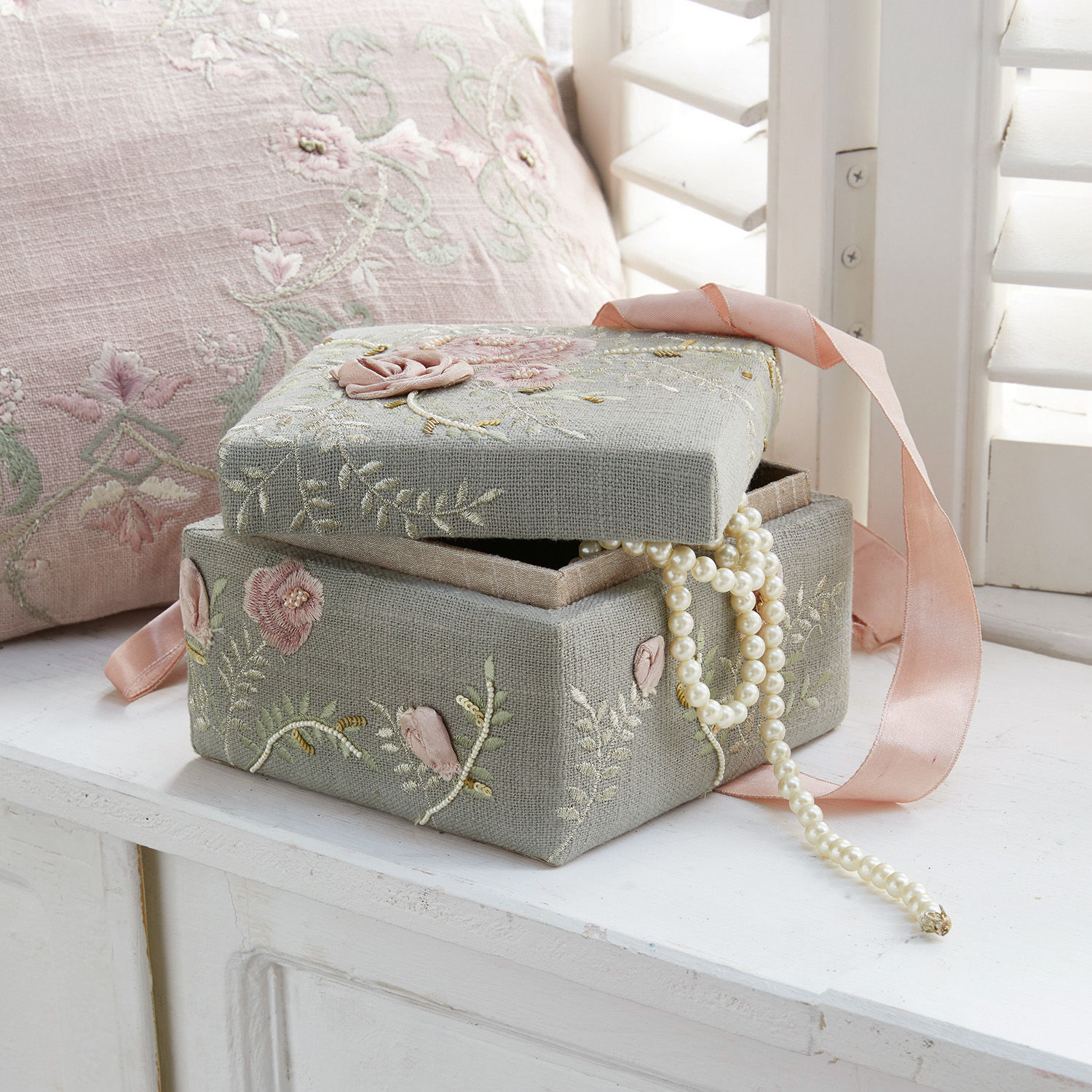 Graue Schmuckschachtel aus Leinen mit Blumenstickerei und rosa Band, Perlenkette hervorstehend
