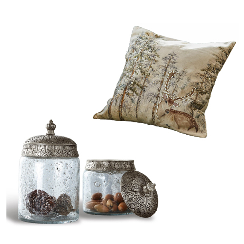 Gläser mit verzierten Metalldeckeln und Kissen mit Hirschmotiv im Wald