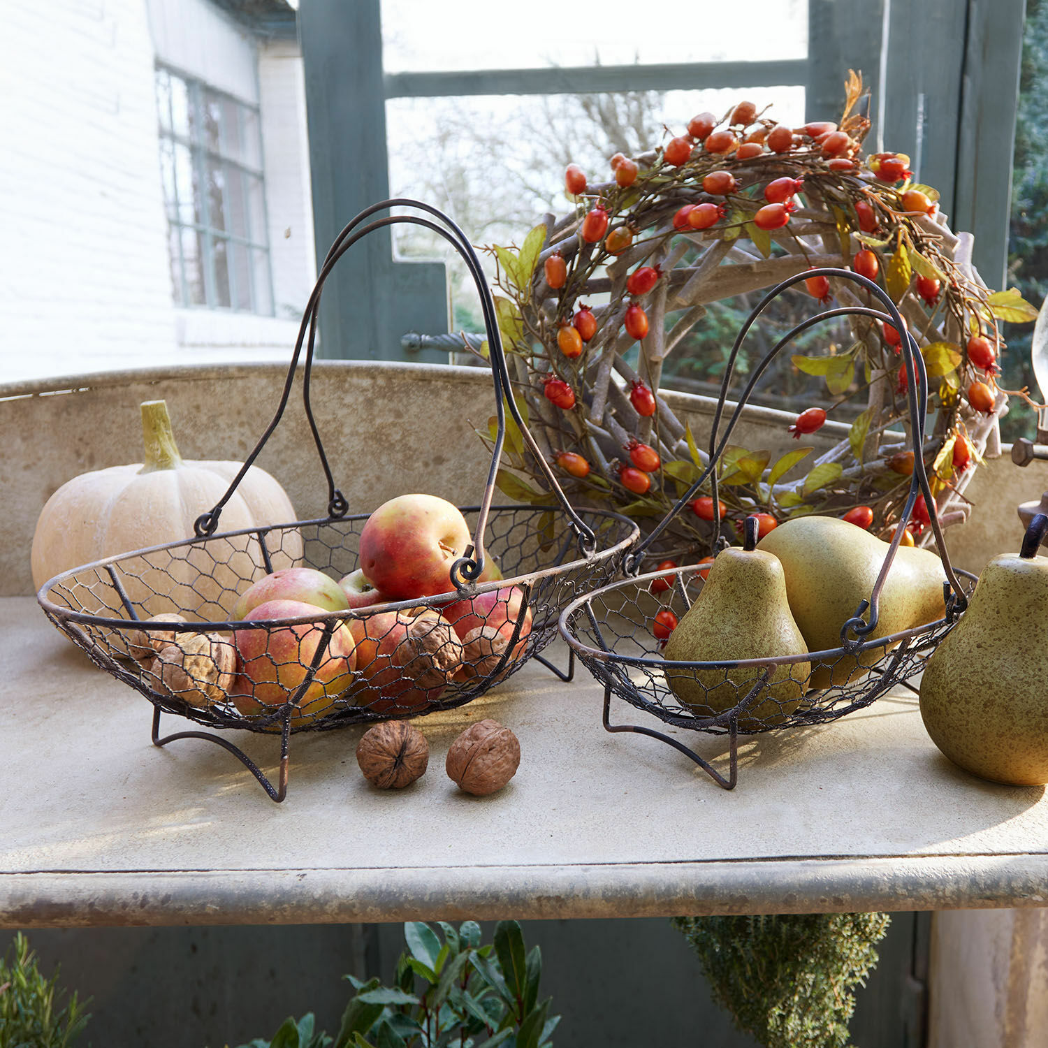 Korb 2er Set Serrie Zwei Metallkörbe mit Griffen, gefüllt mit Äpfeln und Birnen, herbstliche Dekoration im Landhausstil.