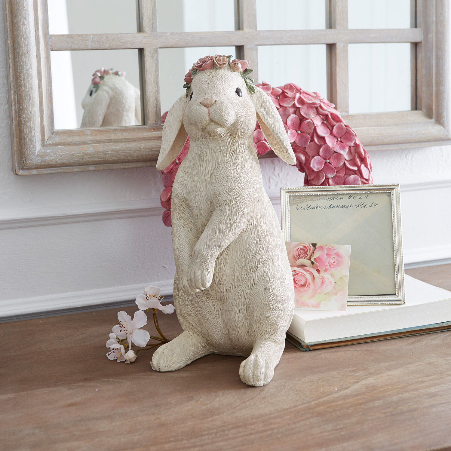 Hase Sweety Kaninchenfigur aus cremefarbenem Material mit rosafarbenem Blumenkranz auf dekoriertem Tisch