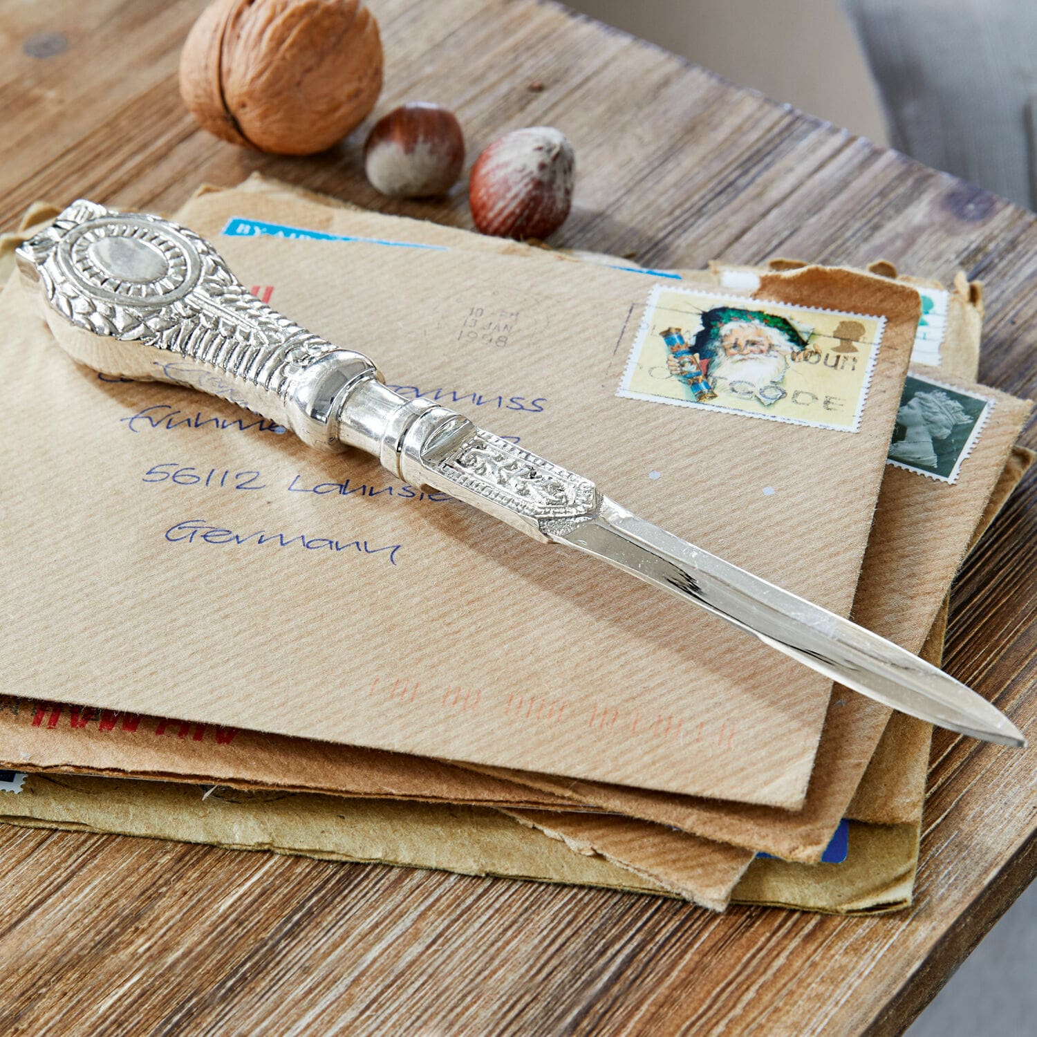 Brieföffner Parsifal Verziertes silbernes Briefmesser auf Briefumschlägen mit Nüssen auf Holztisch