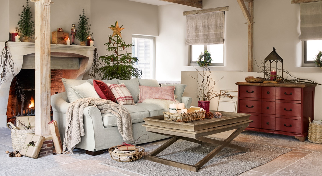 Gemütliches Wohnzimmer mit hellgrauem Sofa, Holzcouchtisch und rotem Sideboard, weihnachtliche Dekoration