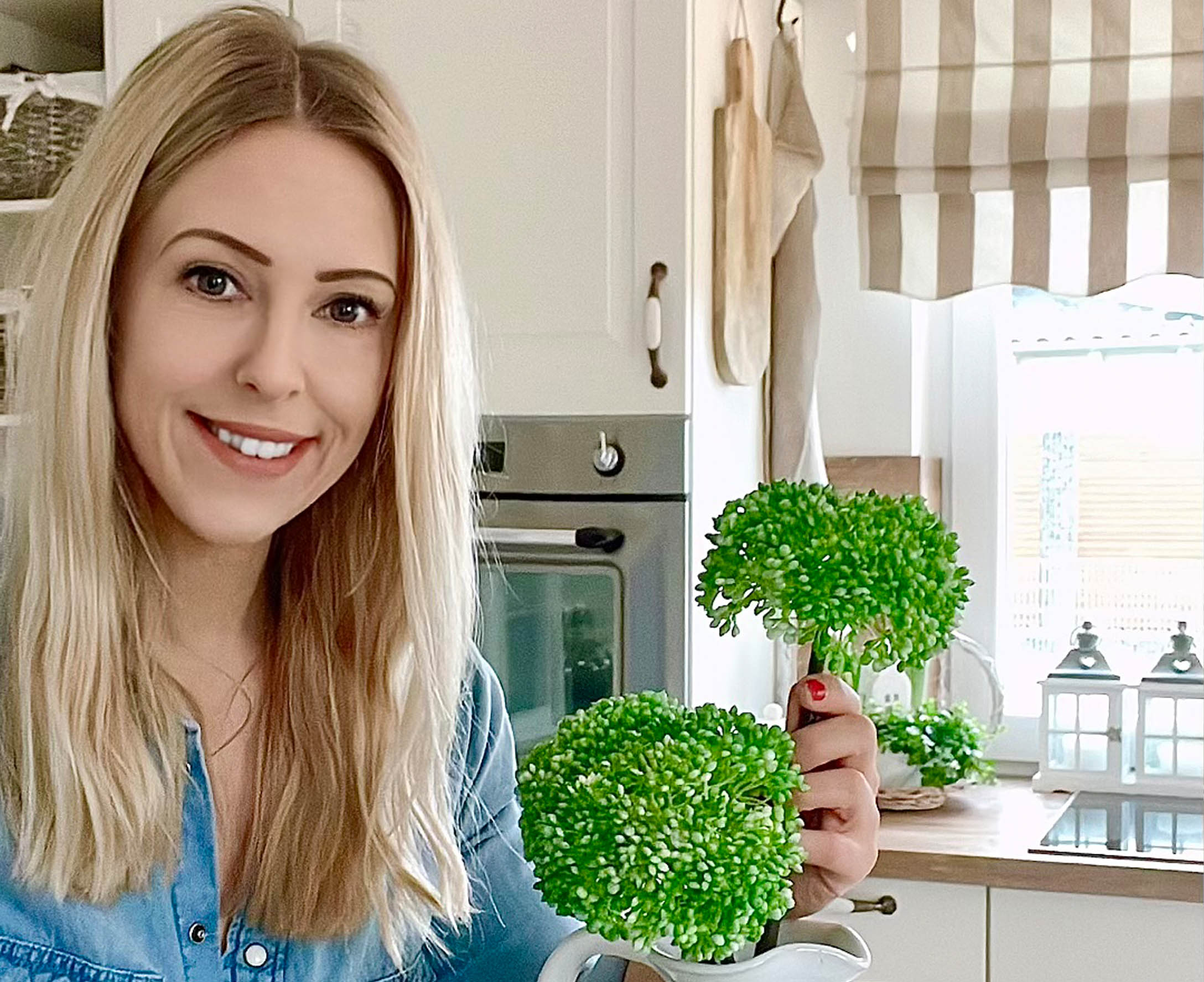 Frau in der Küche hält grüne Dekoblumen in einem weissen Krug, rustikaler Landhausstil.