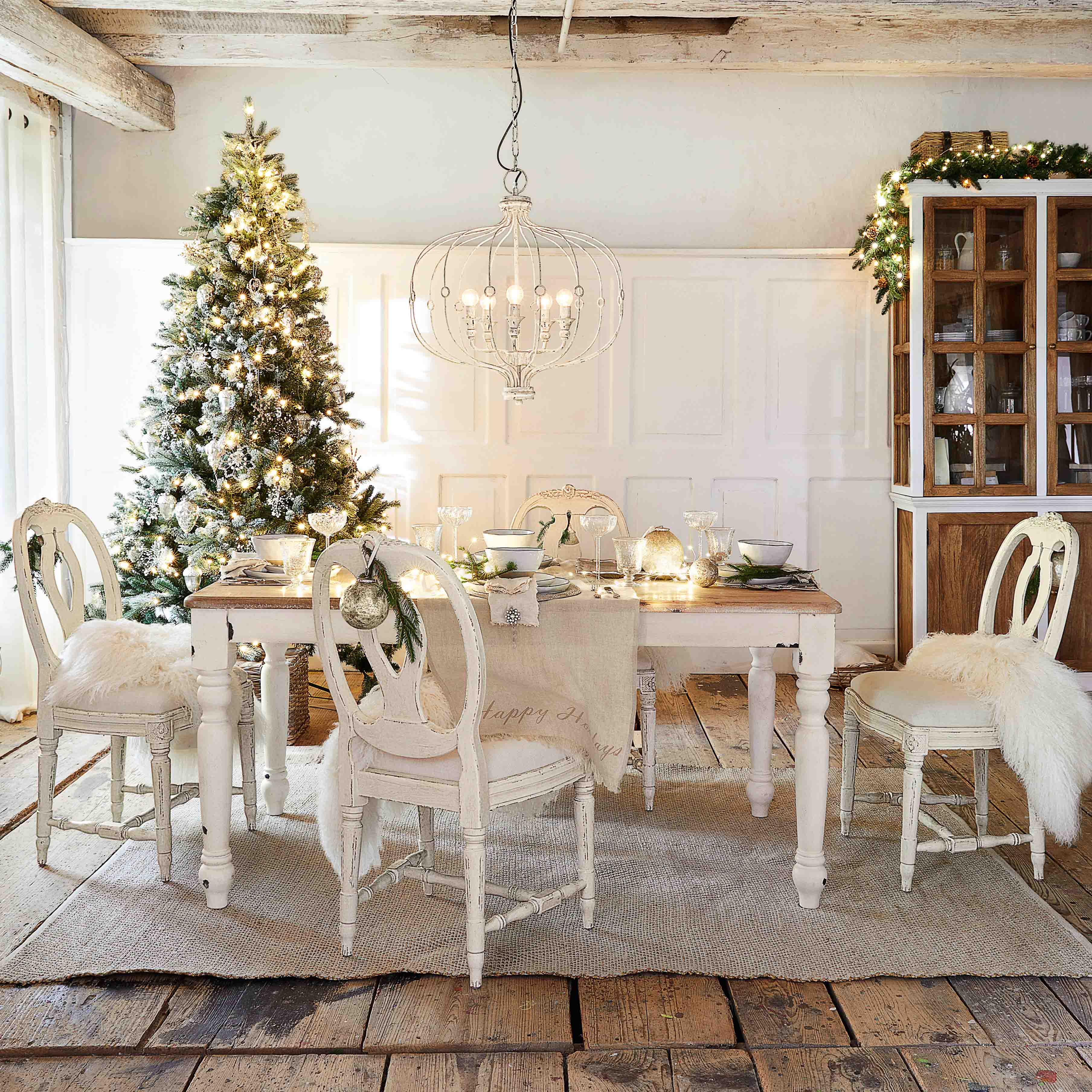 Rustikaler Essbereich mit weissem Holztisch und Stühlen, festlich dekoriert mit Weihnachtsbaum und Leuchte