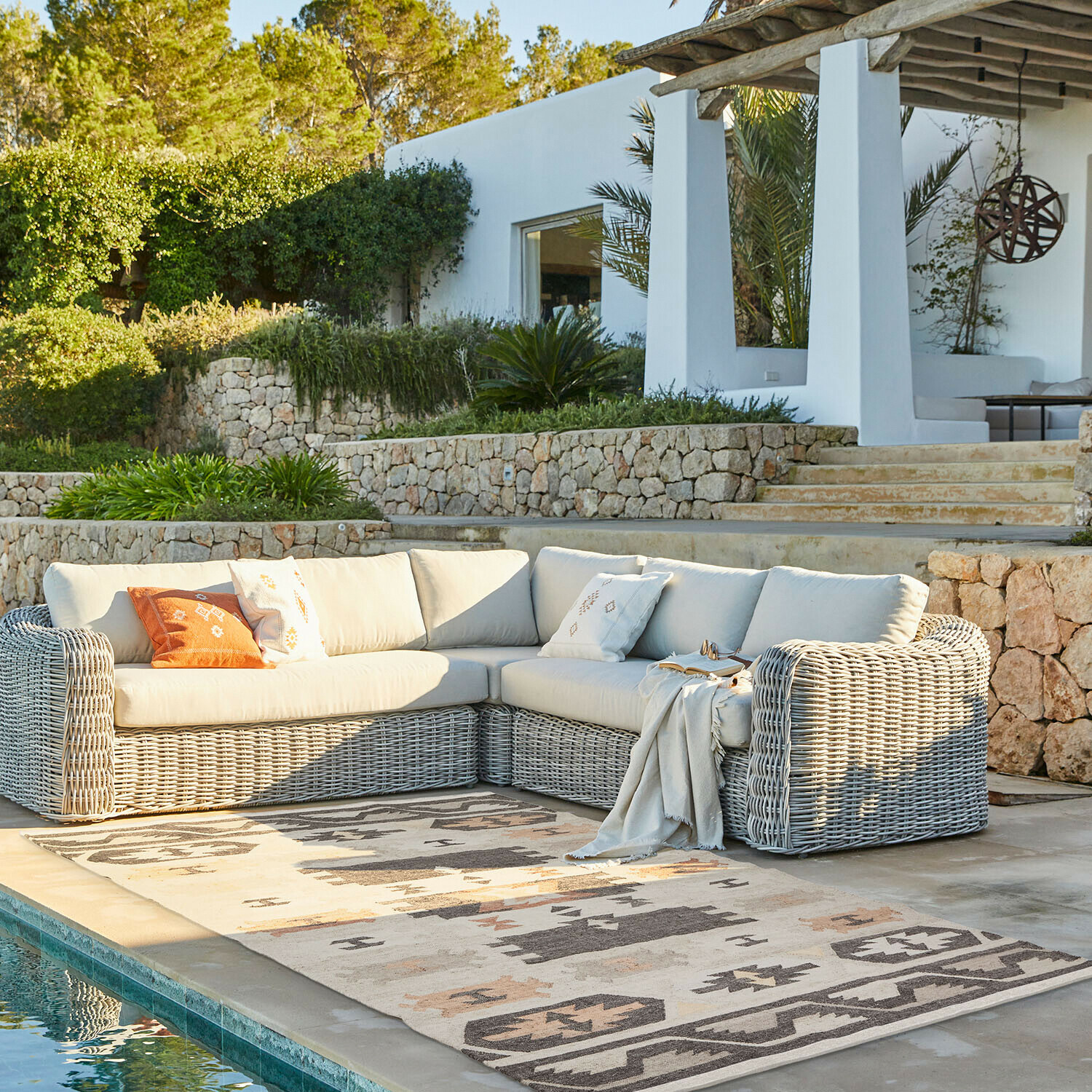 In- & Outdoor-Teppich Selamir Eck-Gartensofa aus grauem Rattan mit hellen Polstern neben dem Pool