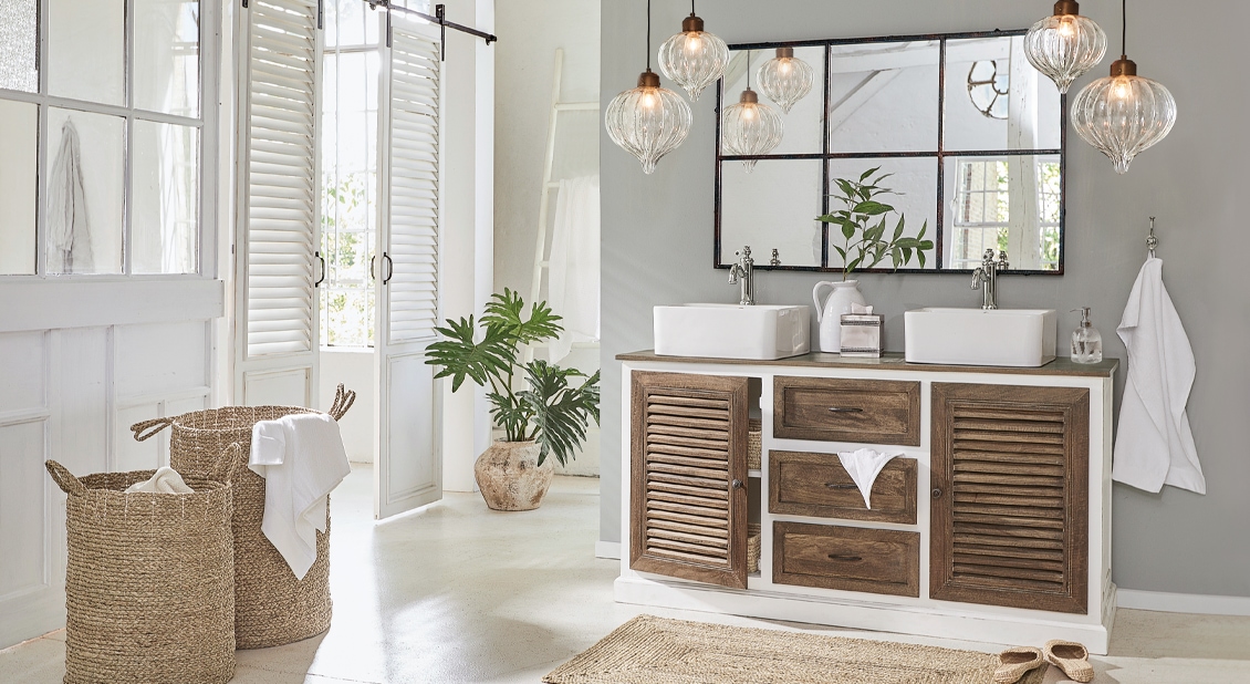 Badezimmer mit Holzschrank, weissem Waschbecken und naturfarbenem Korb aus Seegras für Wäsche